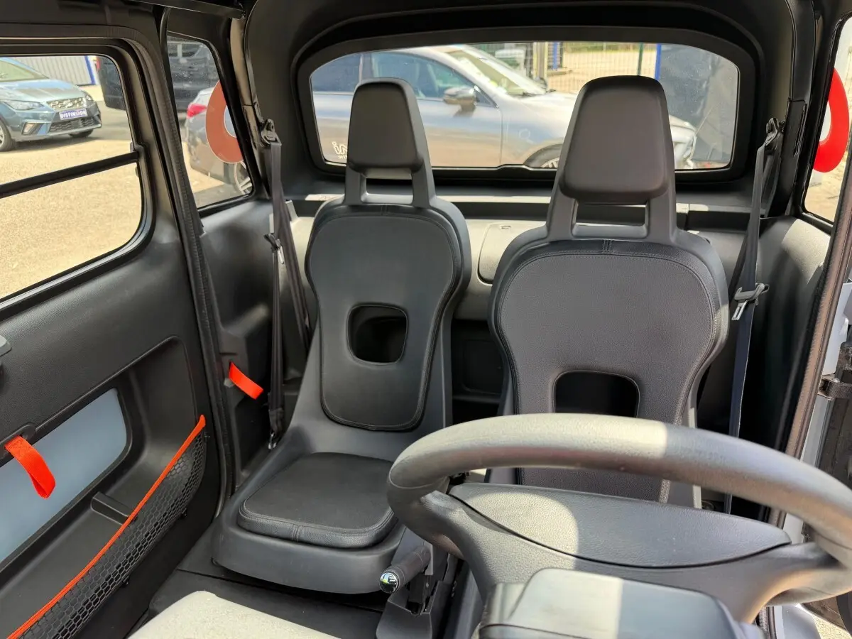 Vue intérieure avant de la Citroën Ami MY AMI POP 2024 avec sièges noirs minimalistes et volant visible.