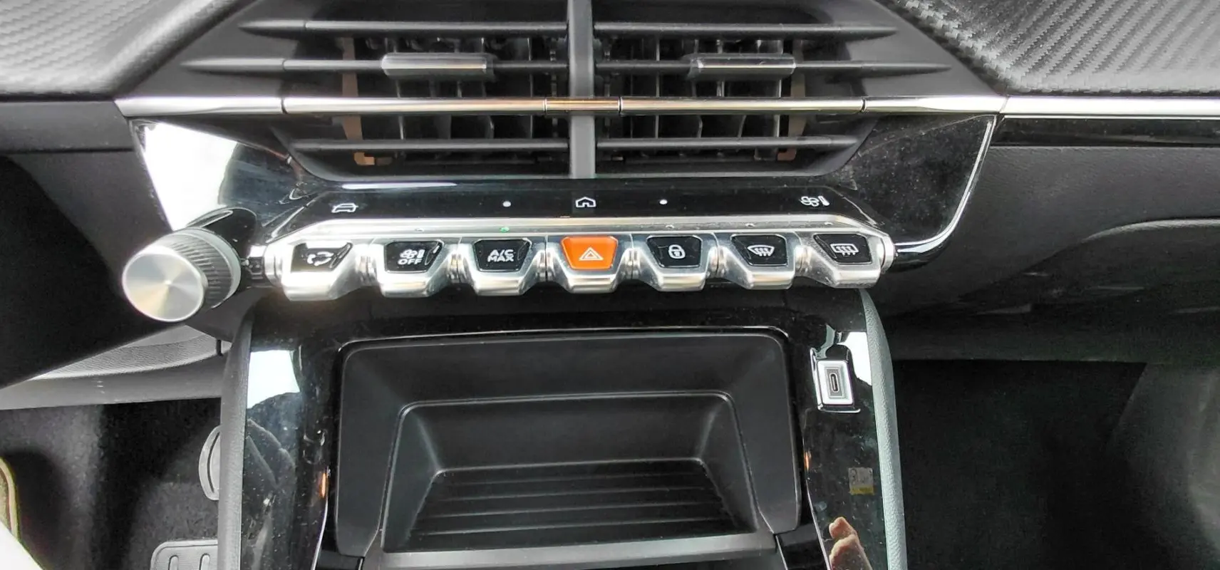 Vue rapprochée de la console centrale du Peugeot 2008 Hybrid 145 Style 2025 noir, avec boutons chromés et bouton orange d’alerte.