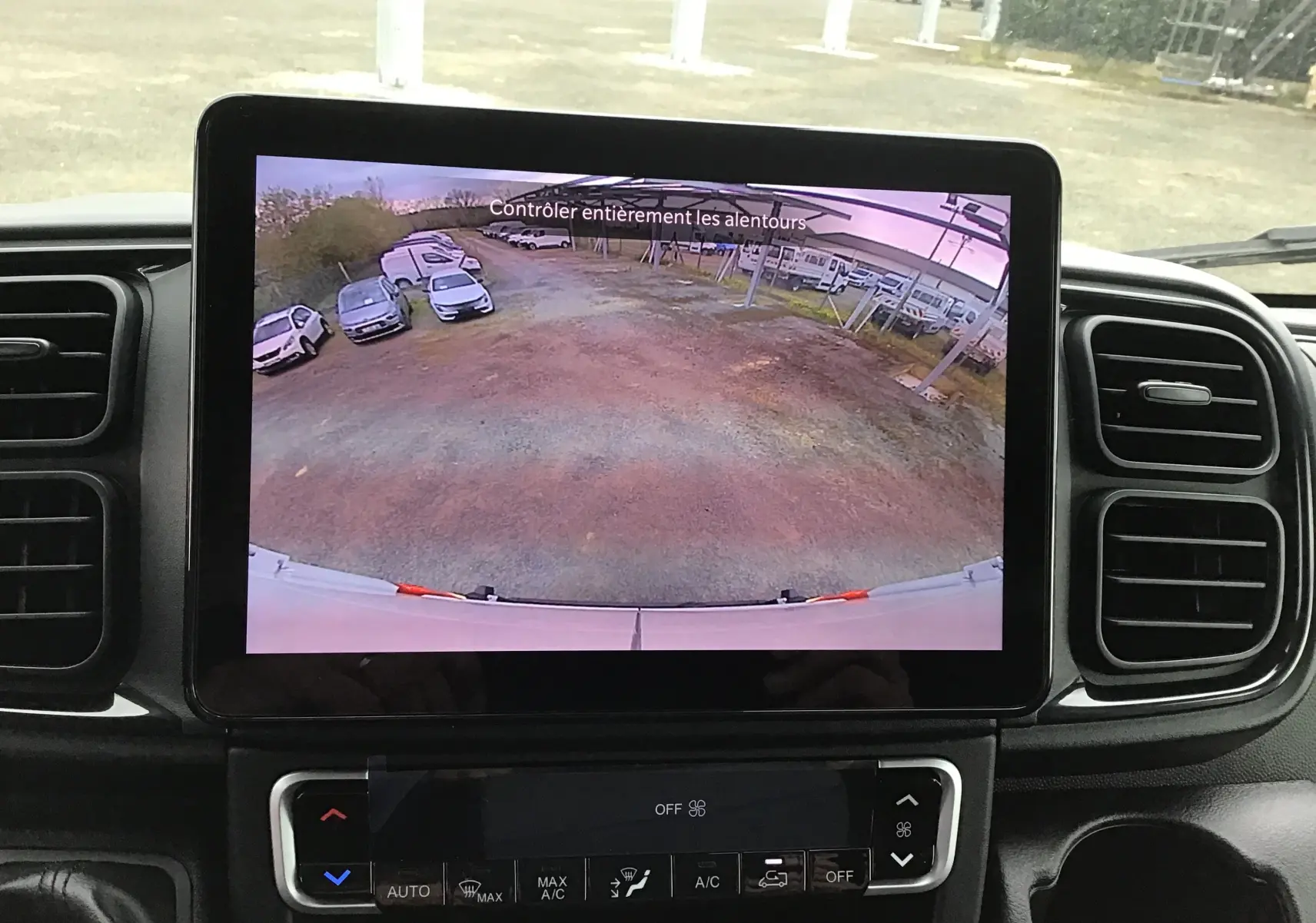 Écran intérieur du Peugeot Boxer Fourgon blanc montrant la caméra de recul avec vue arrière dégagée sur un parking.