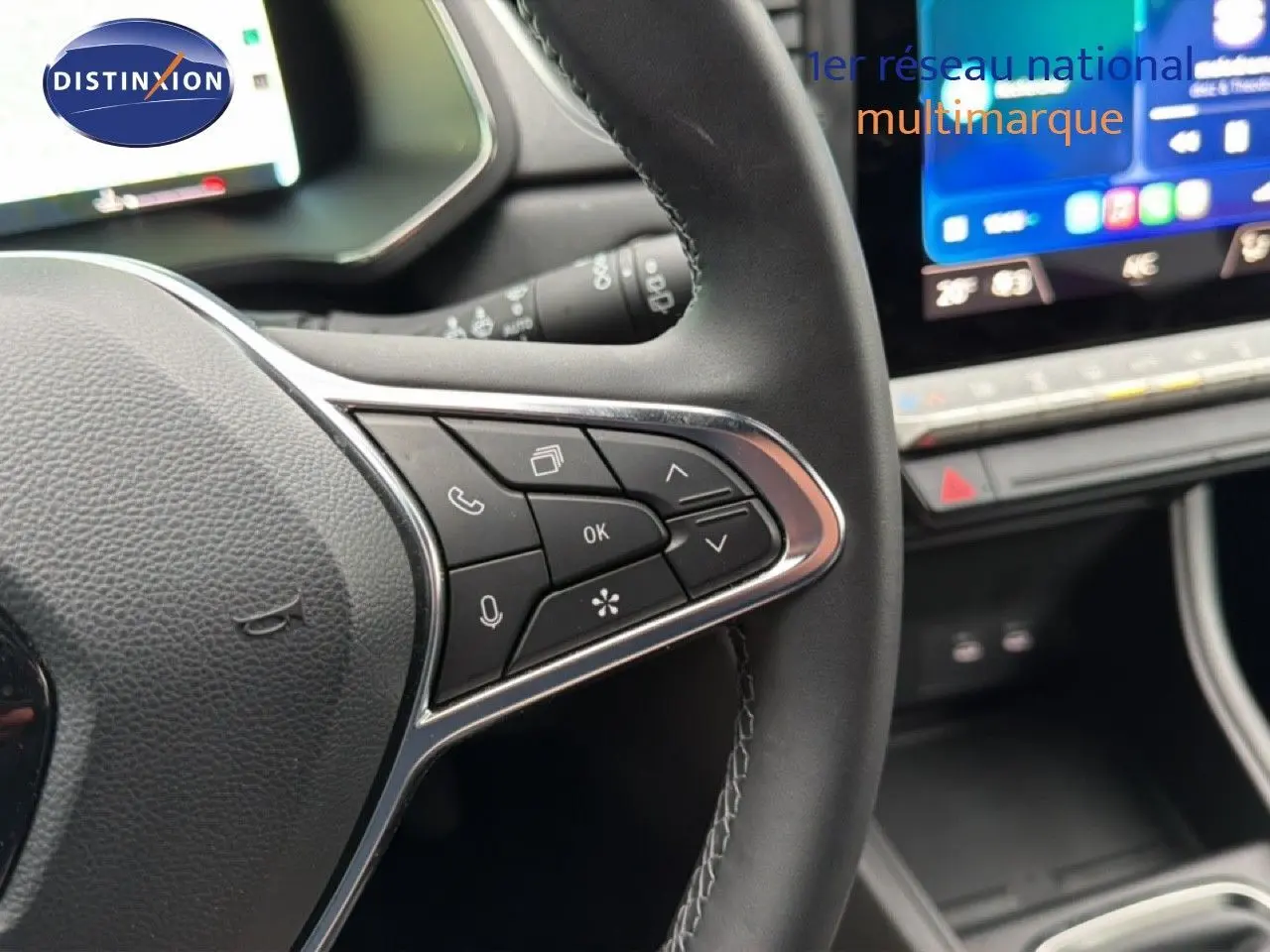 Gros plan sur le volant côté gauche du Renault Captur bleu Iron Metal, avec commandes intégrées et tableau de bord numérique.