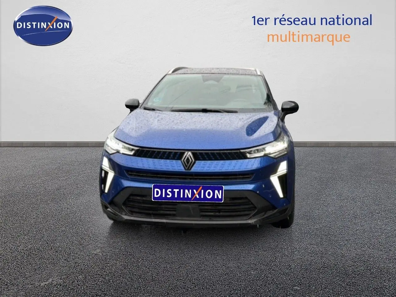 Vue de face du Renault Captur 2025 bleu Iron Metal avec calandre et feux LED distinctifs allumés.