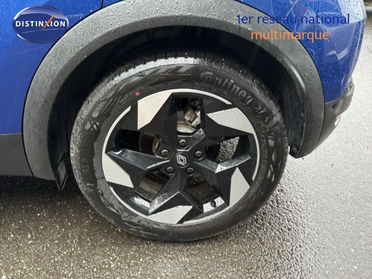 Gros plan sur la roue avant droite du Renault Captur bleu Iron Metal avec jante noire et argentée au design étoilé.