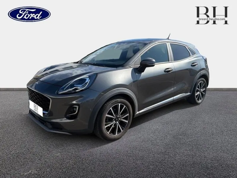Ford Puma 2024 gris métallisé vu en 3/4 avant droit avec jantes noires et vitres arrière surteintées.
