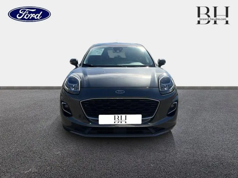 Vue frontale d'une Ford Puma 2024 gris métallisé avec calandre noire et phares arrondis.