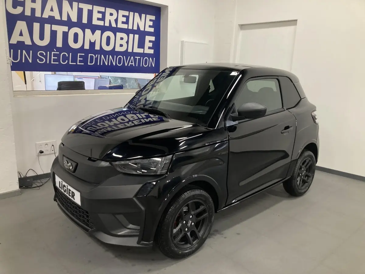 Vue 3/4 avant droite de la Ligier JS50 noire 2026 avec jantes alu noires et feux à LED en intérieur showroom.