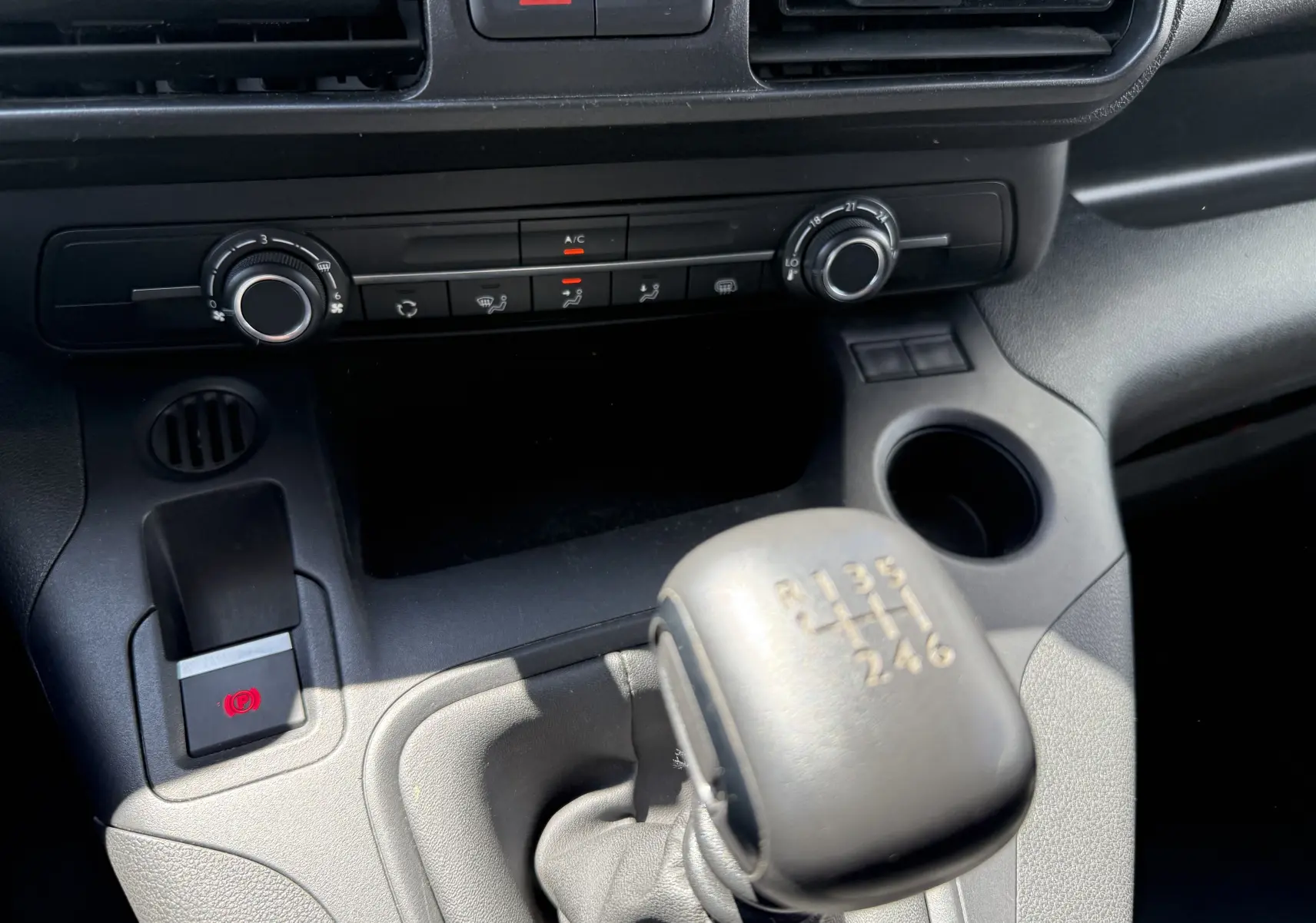 Gros plan sur la commande de boîte manuelle et la console centrale noire du Citroën Berlingo XL blanc banquise 2022.