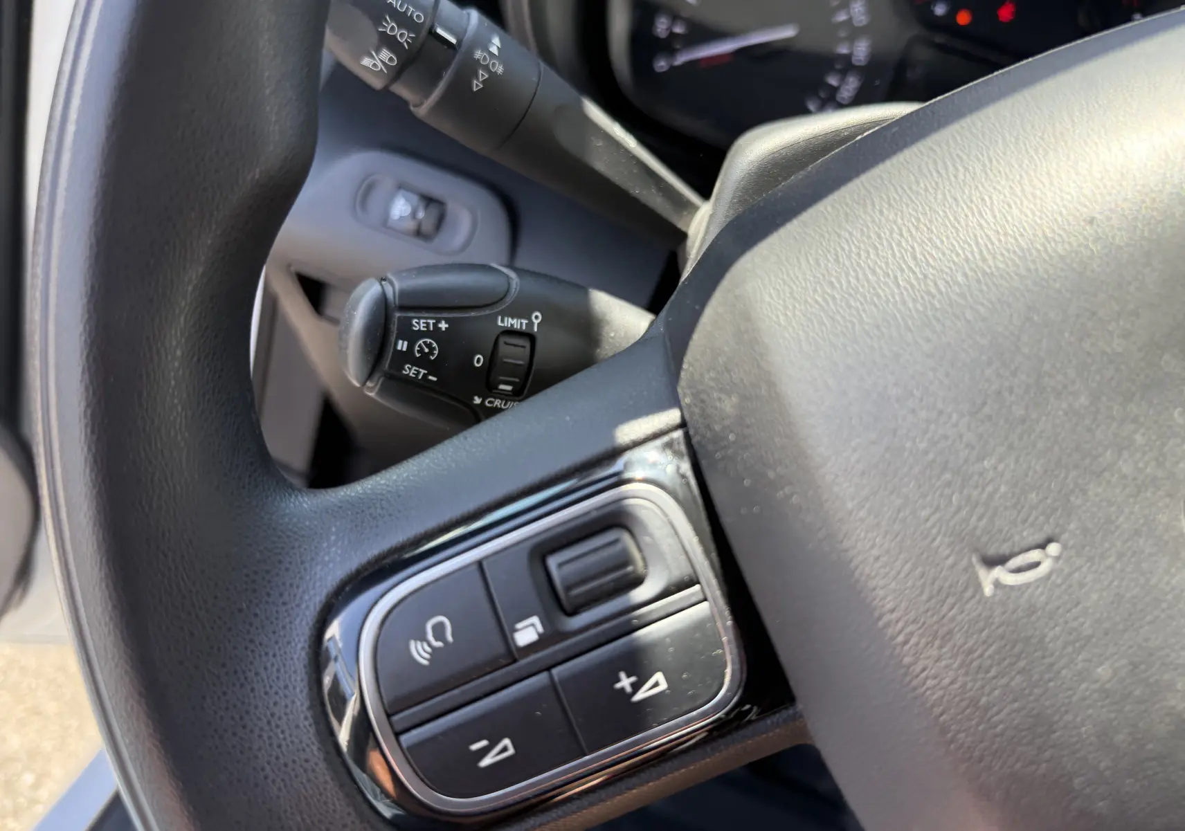 Gros plan sur le volant côté gauche du Citroën Berlingo blanc banquise 2022, avec commandes audio et régulateur de vitesse.
