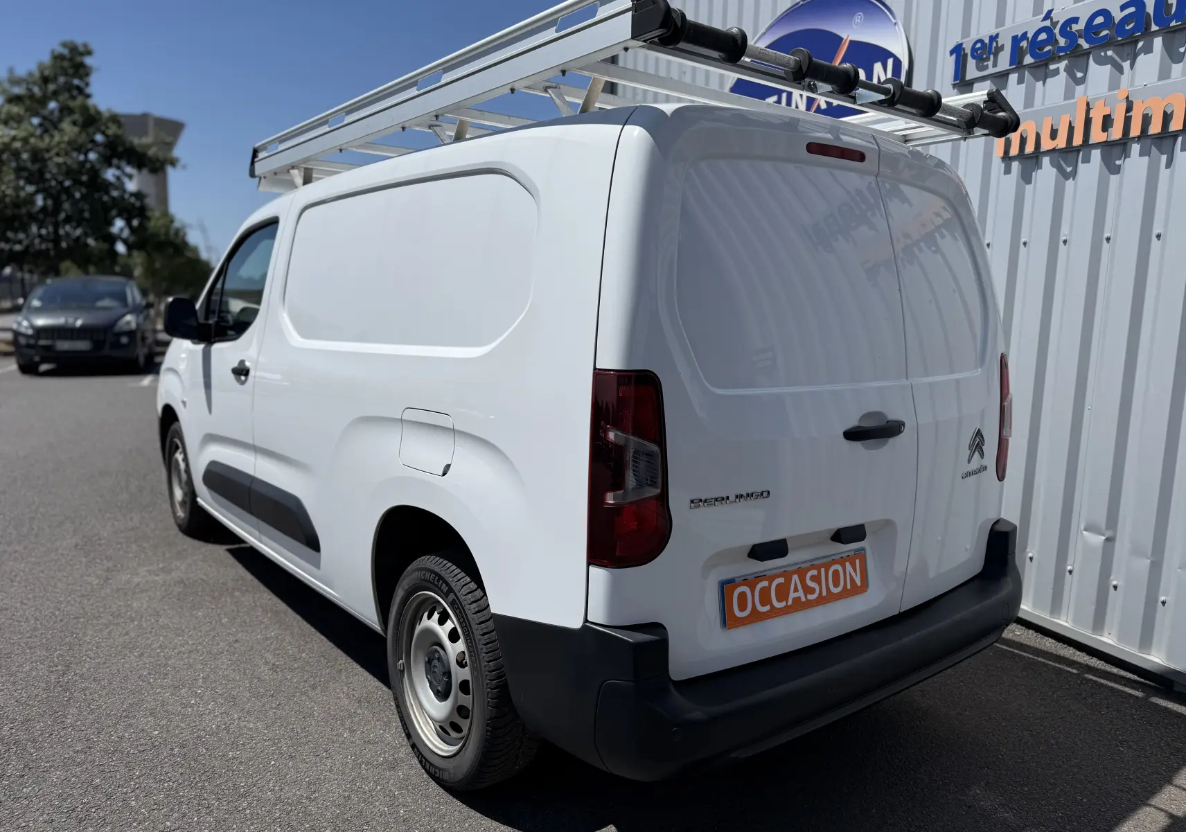 Vue 3/4 arrière droite d’un Citroën Berlingo XL blanc banquise avec galerie de toit et plaque "OCCASION".