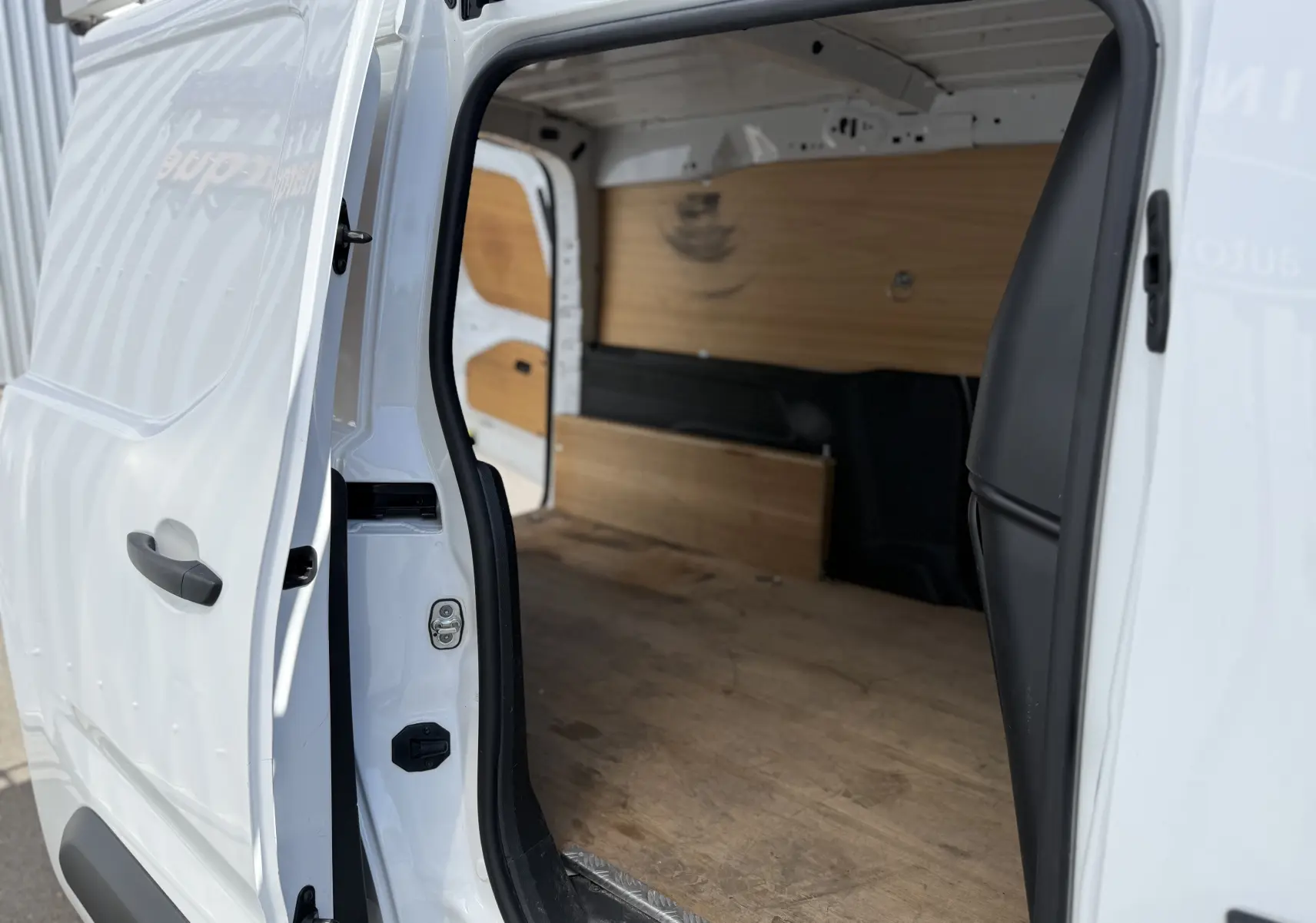 Vue intérieure côté droit du Citroën Berlingo XL blanc banquise avec porte coulissante ouverte et aménagement bois.