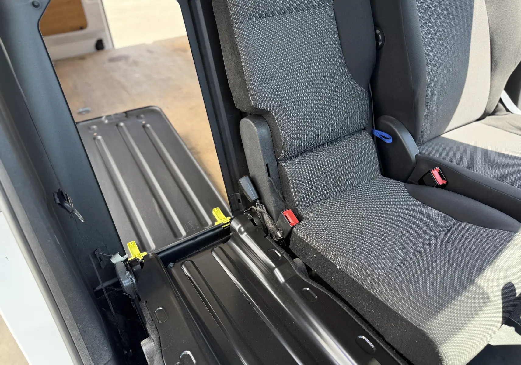 Vue intérieure rapprochée côté droit du siège arrière gris tissu du Citroën Berlingo XL blanc banquise avec plancher métallique visible.
