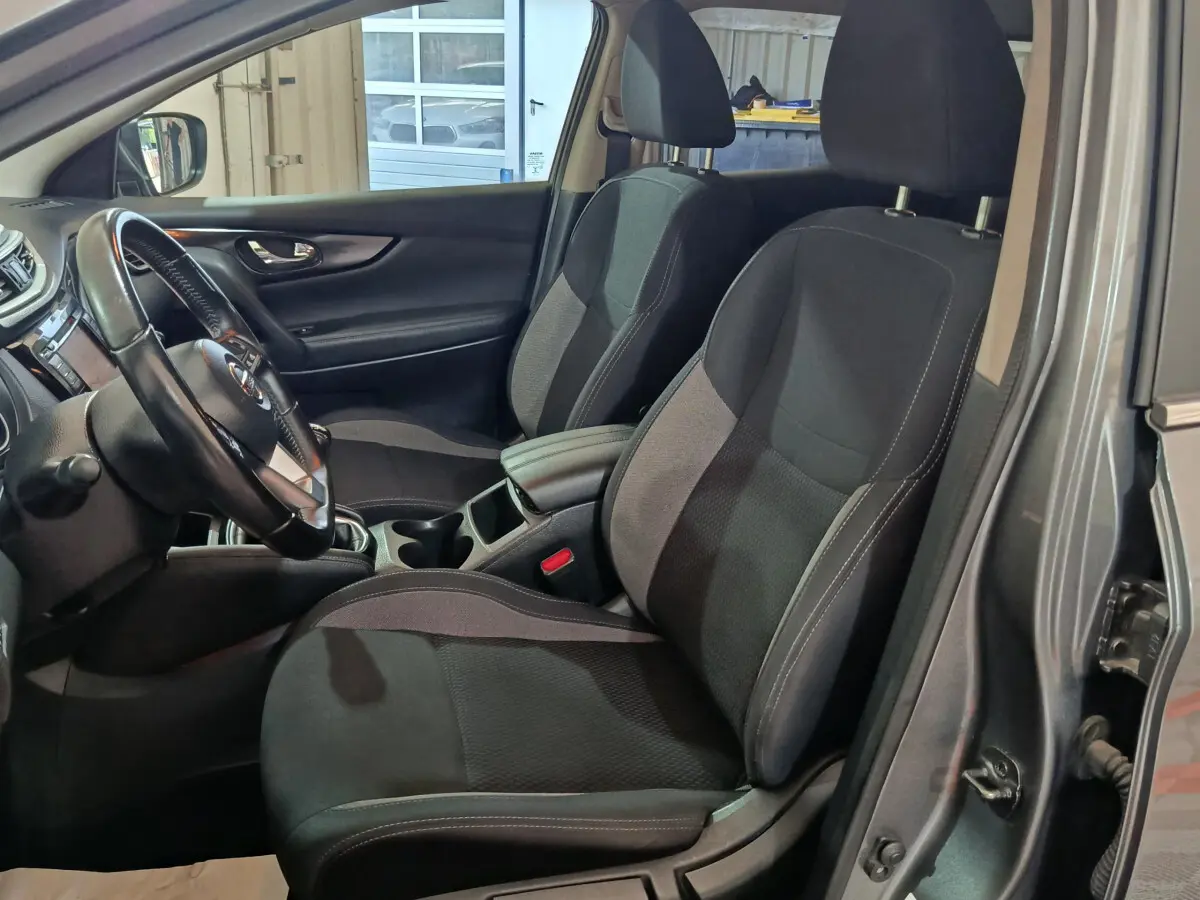 Intérieur du Nissan Qashqai gris clair, vue côté gauche sur sièges avant noirs et volant cuir multifonctions.