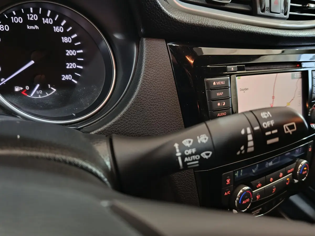Détail intérieur du tableau de bord du Nissan Qashqai 2019 montrant la commande d'essuie-glace et l'écran tactile de navigation.