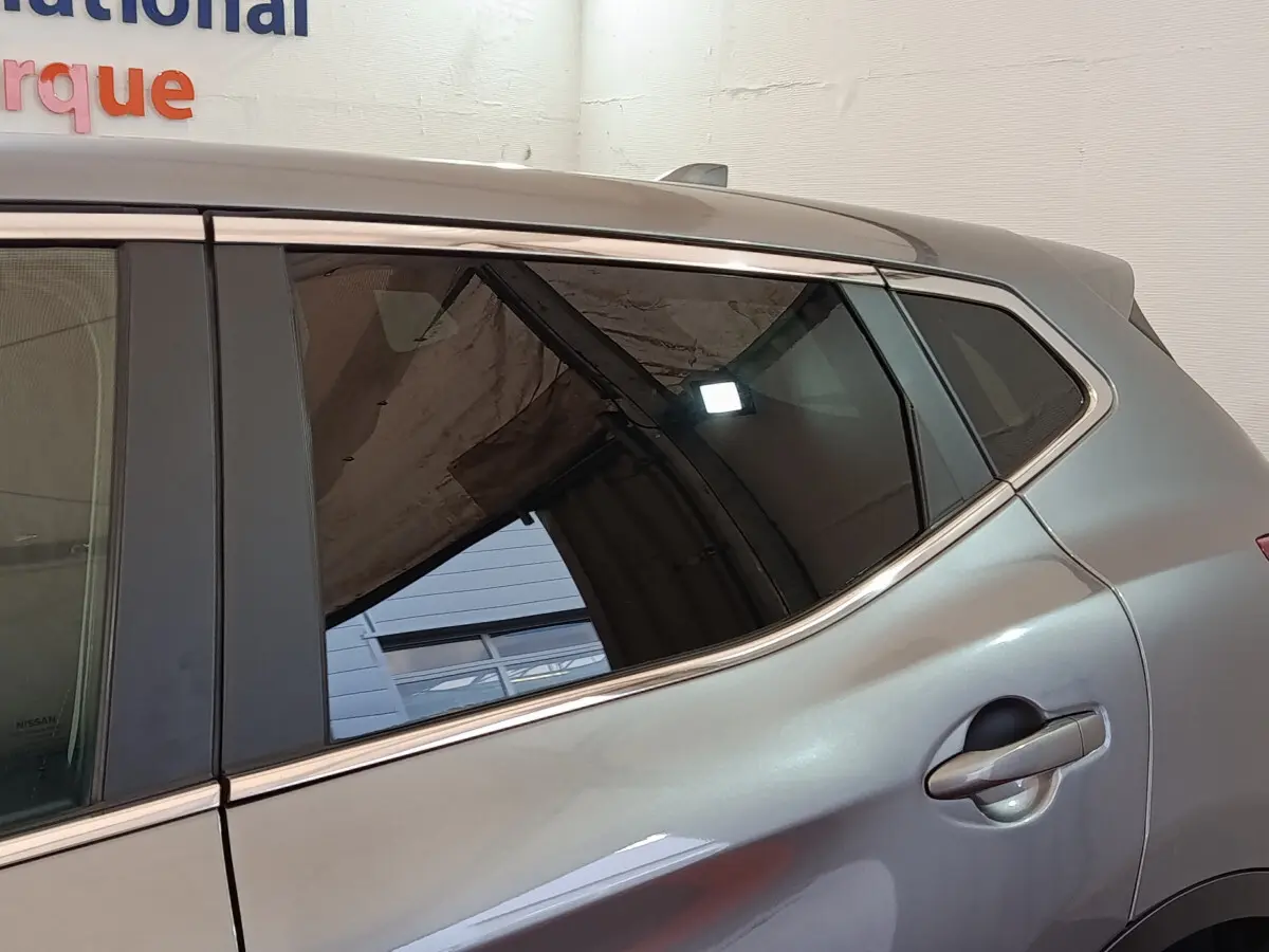 Gros plan sur la porte arrière côté droit d'un Nissan Qashqai gris clair avec poignée intégrée et vitres teintées.