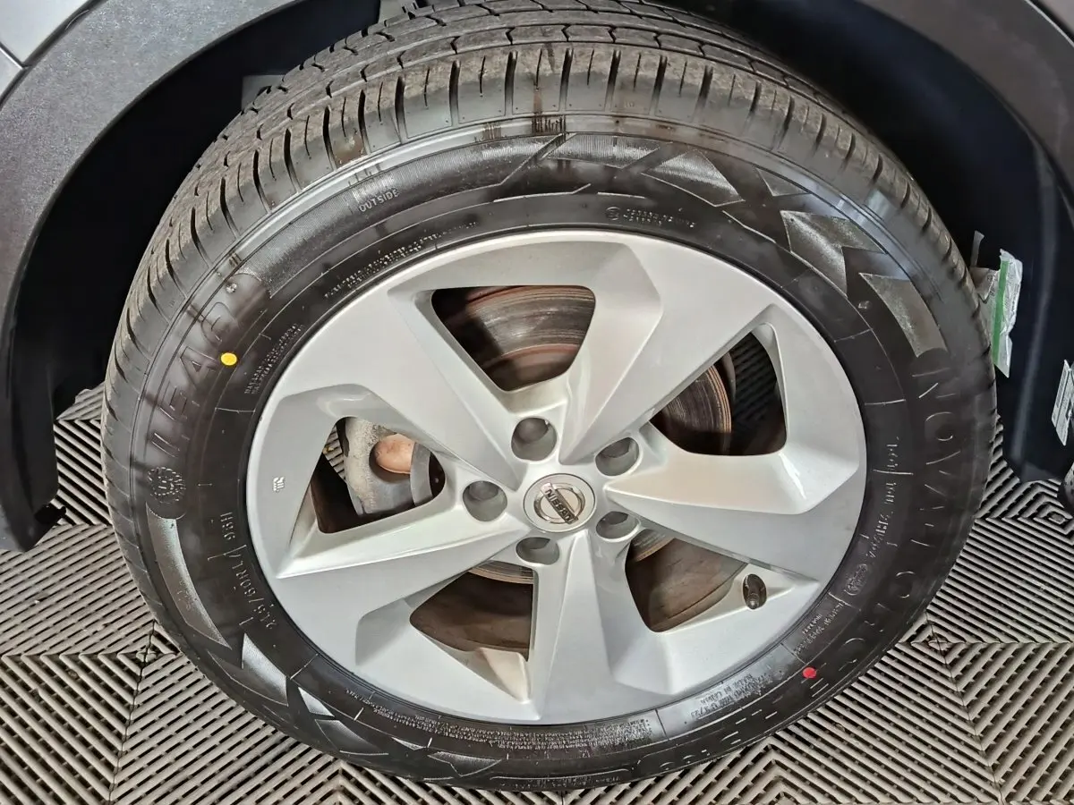 Gros plan sur la roue avant droite du Nissan Qashqai gris clair, jante alliage à cinq branches.