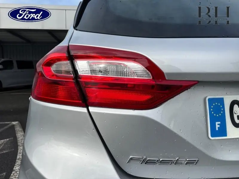 Gros plan sur le feu arrière gauche d'une Ford Fiesta gris lunaire avec logo et plaque d'immatriculation française visible.