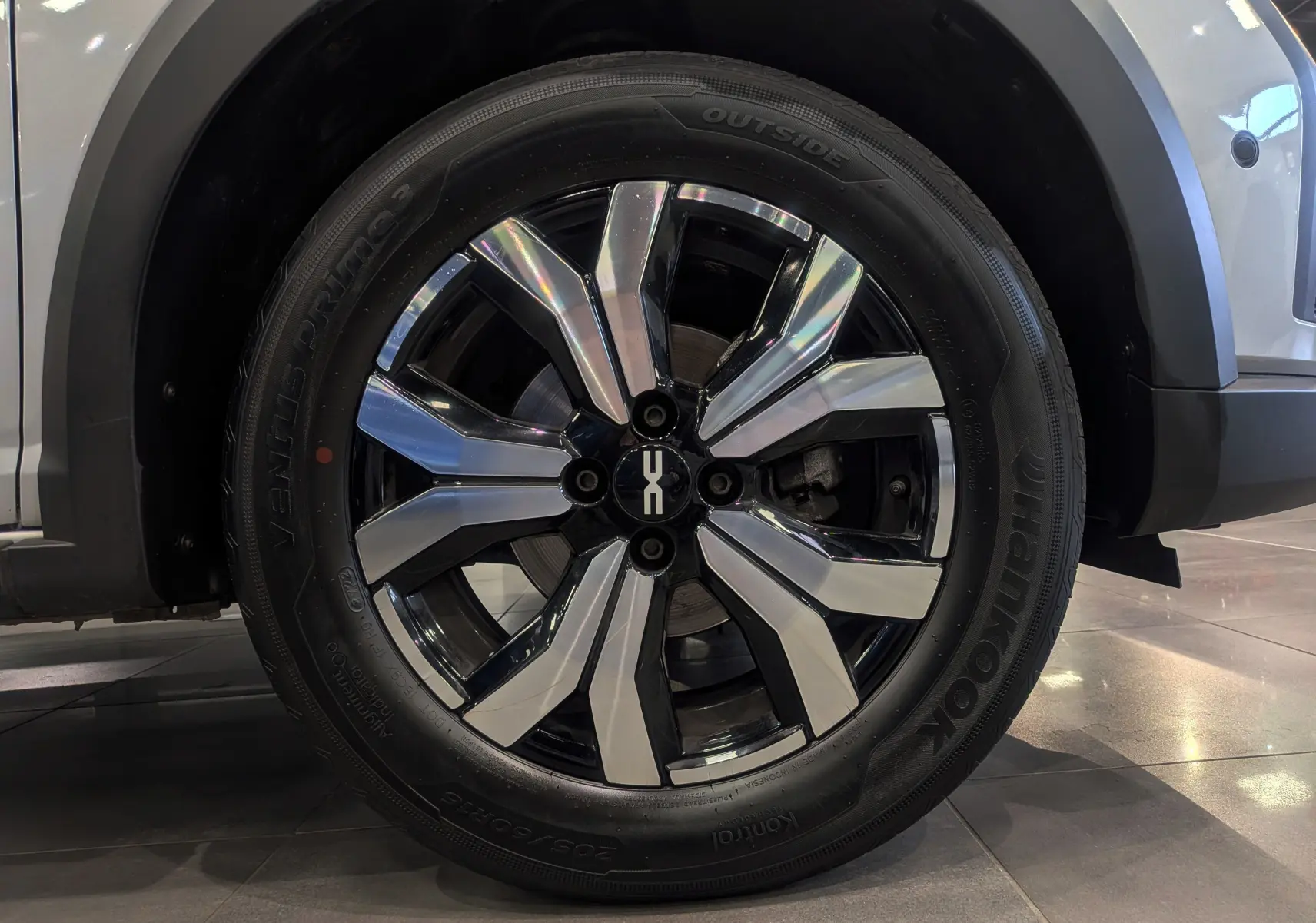 Gros plan sur la roue avant droite de la Dacia Sandero Stepway gris Moonstone, jante alliage bicolore brillante.