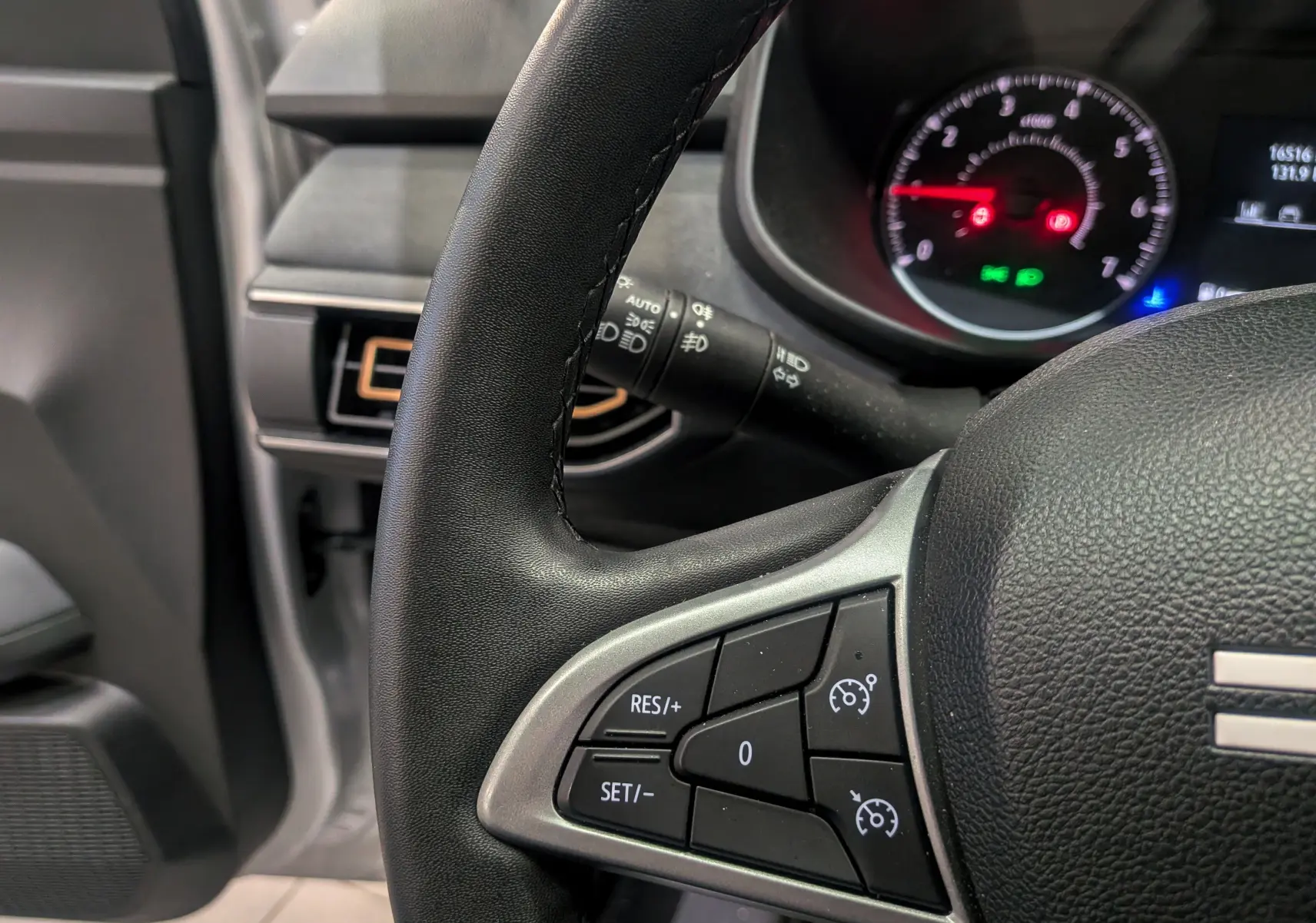 Gros plan sur le volant noir avec commandes de régulateur de vitesse du Dacia Sandero Stepway 2023, intérieur gris.