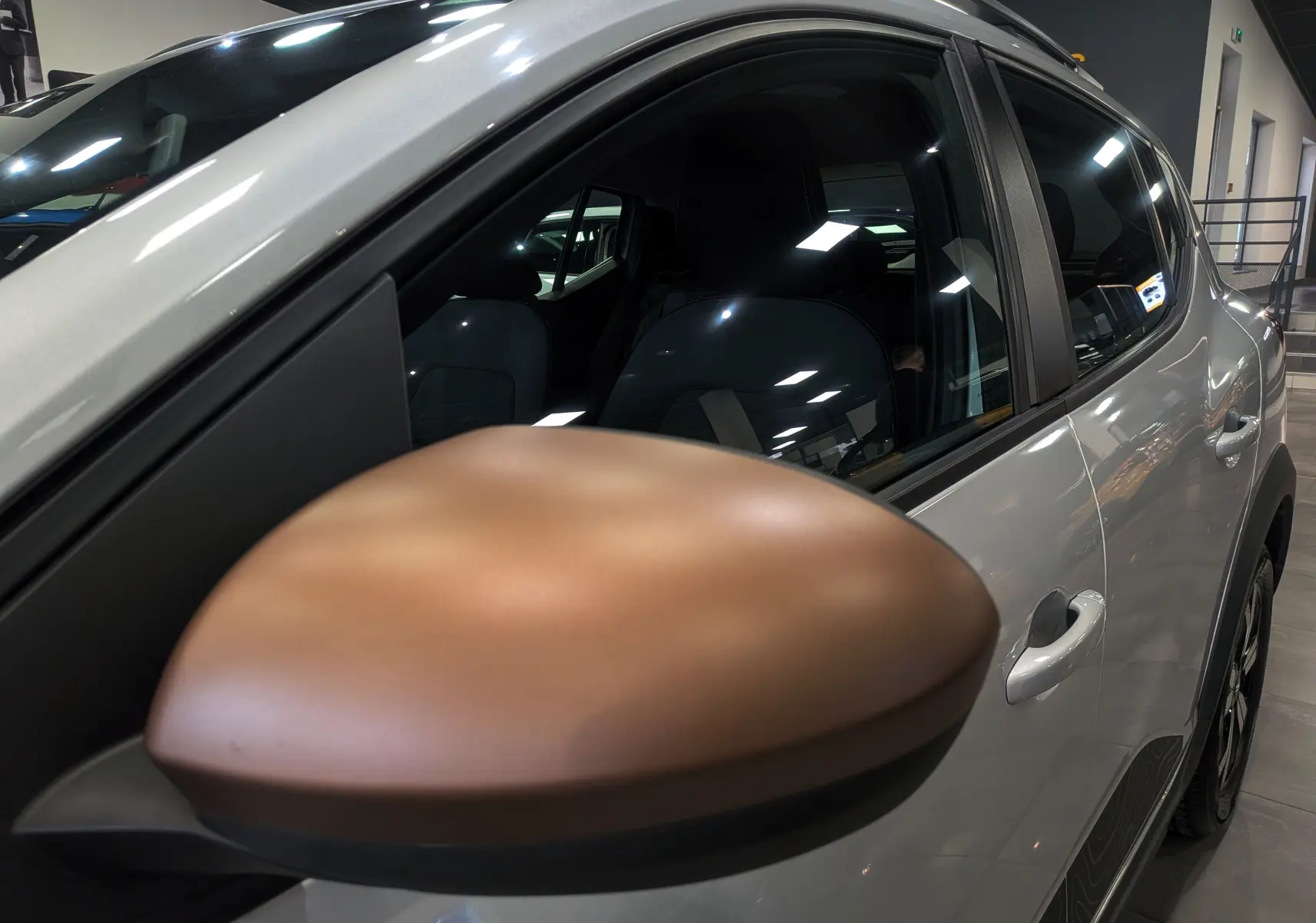 Gros plan sur le rétroviseur marron du côté gauche d'une Dacia Sandero Stepway gris Moonstone, vue latérale intérieure.