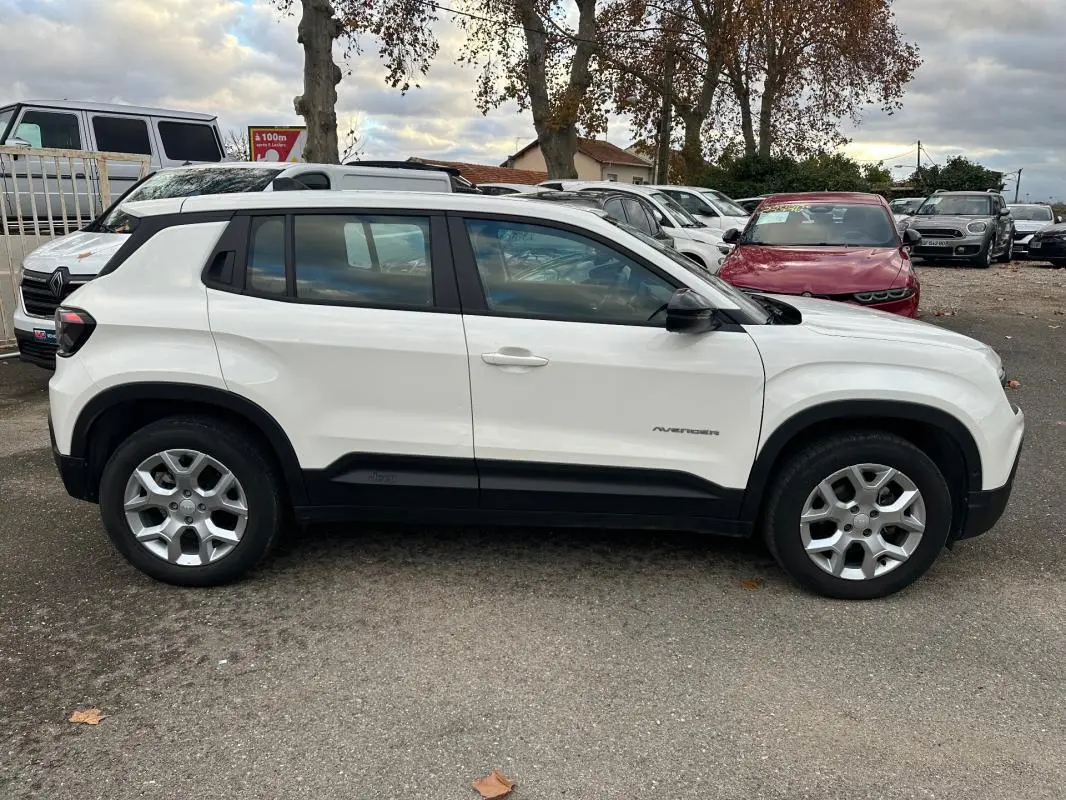Vue de profil côté gauche d’un Jeep Avenger blanc 2024 avec jantes alliage 17 pouces et protections noires sur bas de caisse.