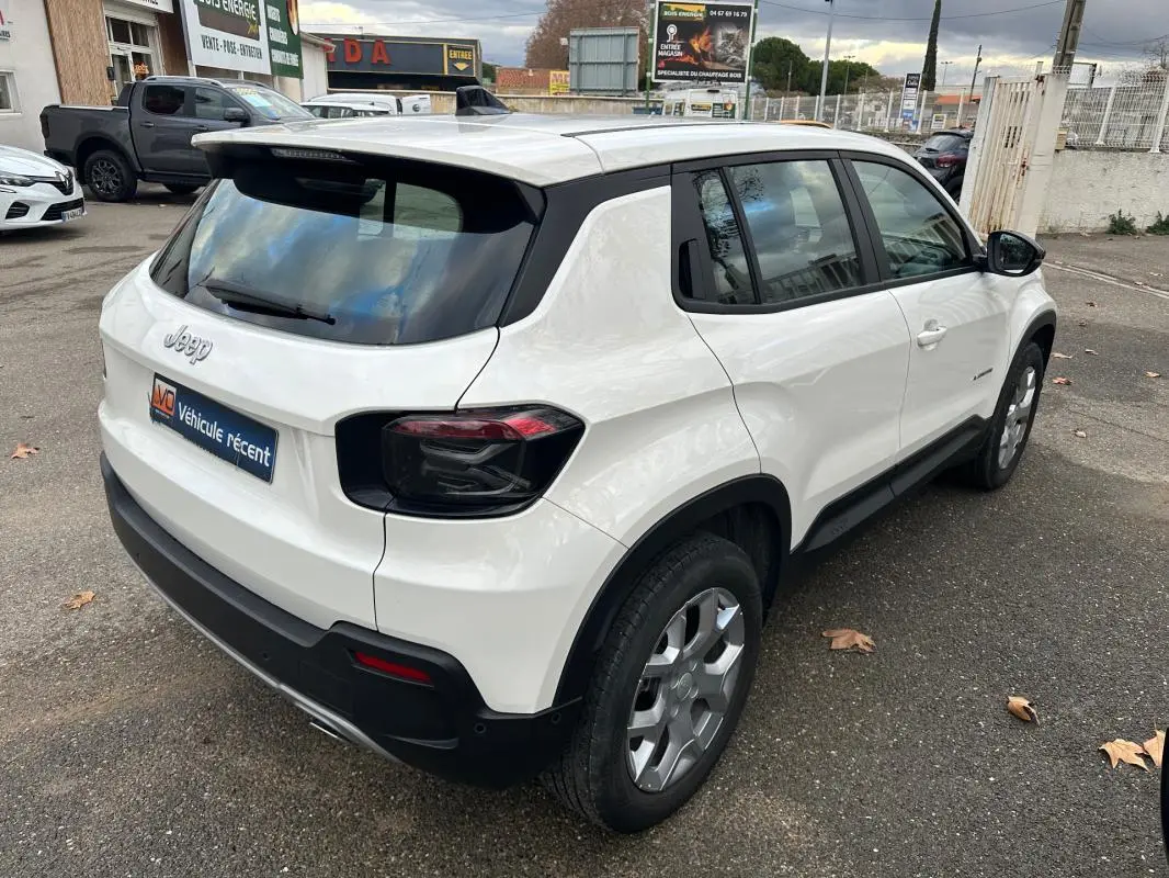 Vue 3/4 arrière droite d’un Jeep Avenger blanc 2024 avec jantes alliage 17 pouces et vitres teintées.