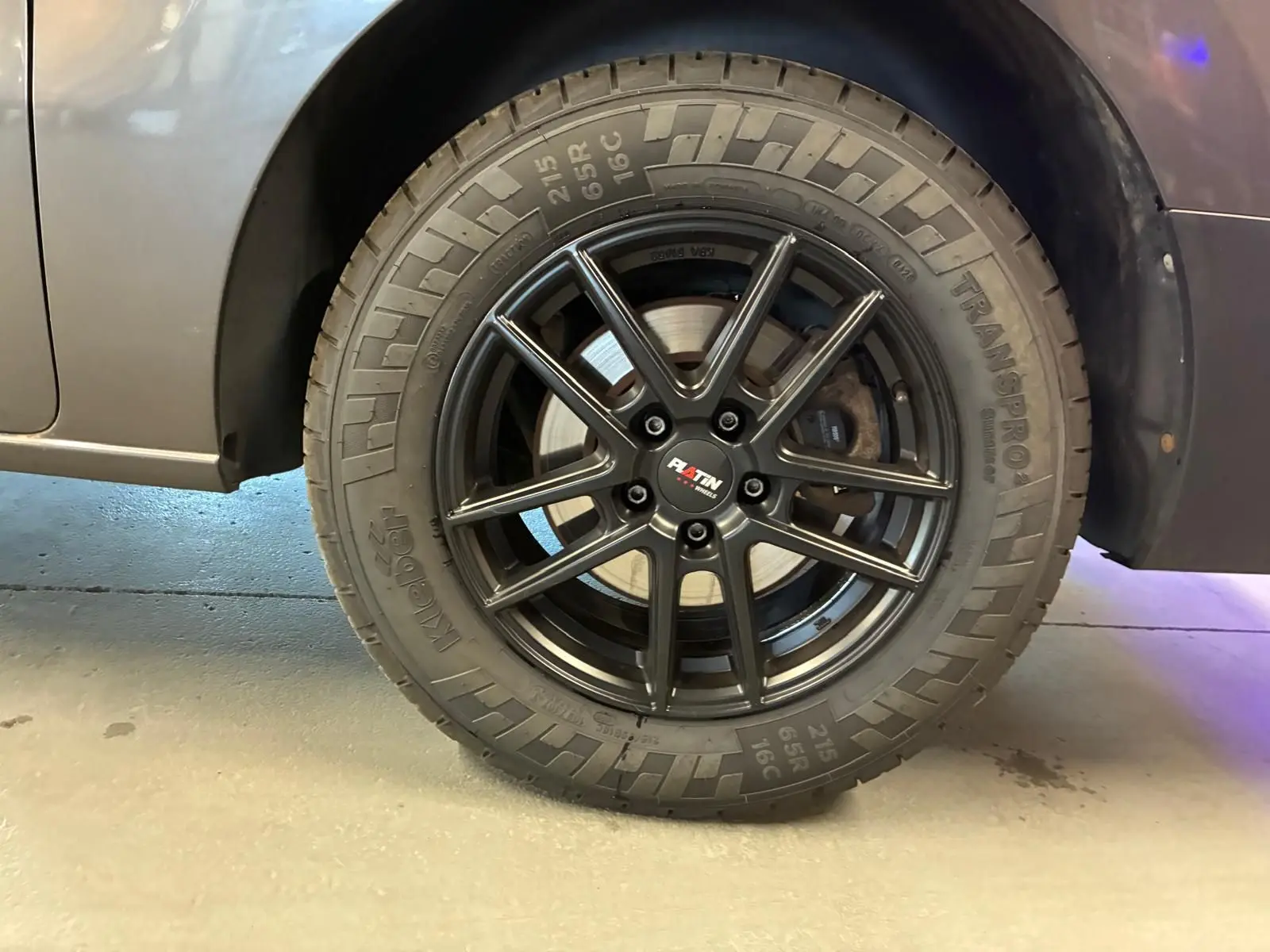 Gros plan sur la roue arrière droite du Citroën Jumpy gris, avec jante noire à dix branches et pneu tout-terrain.