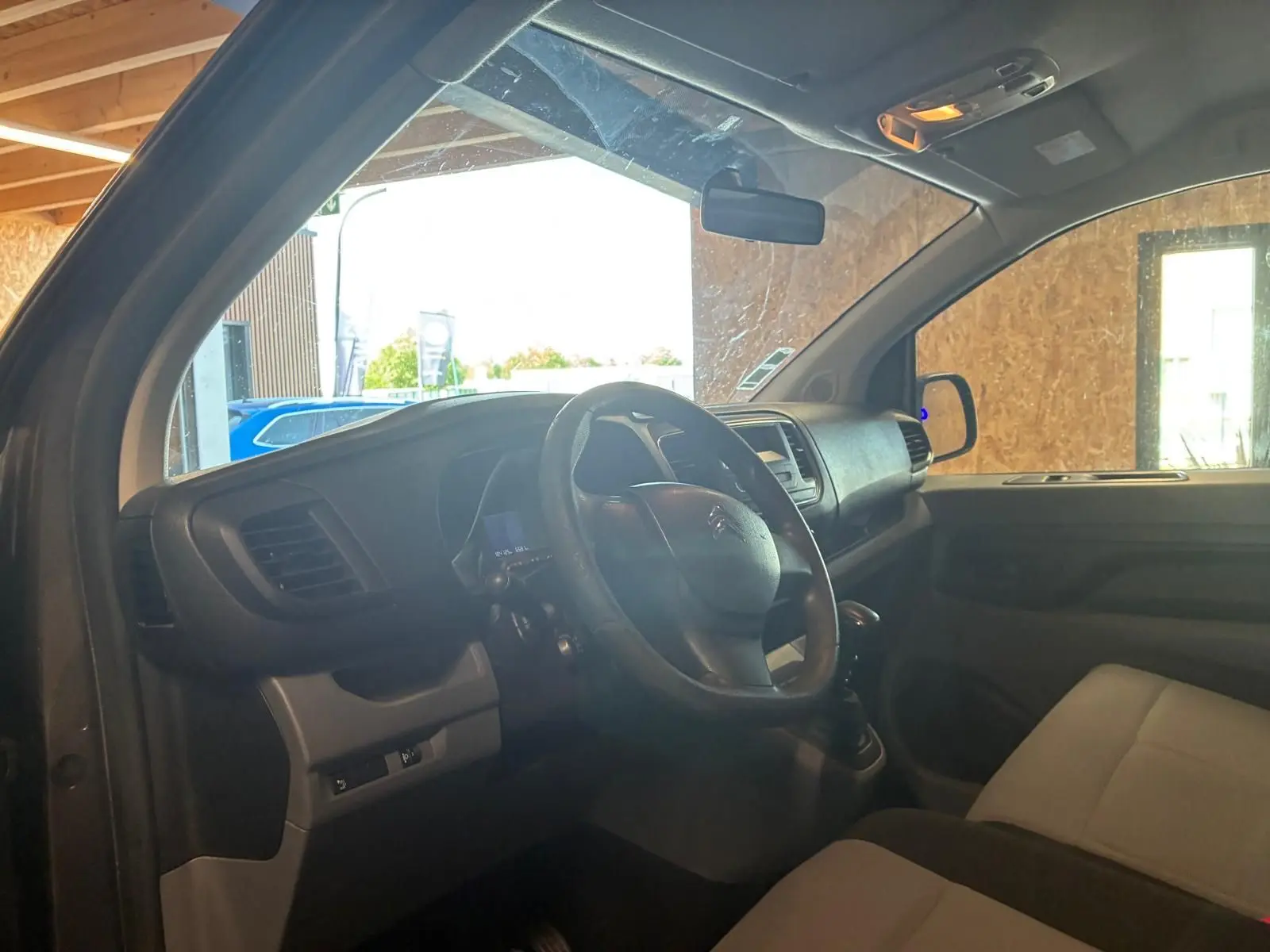 Vue intérieure côté conducteur du Citroën Jumpy gris, montrant le volant, tableau de bord et sièges en tissu.