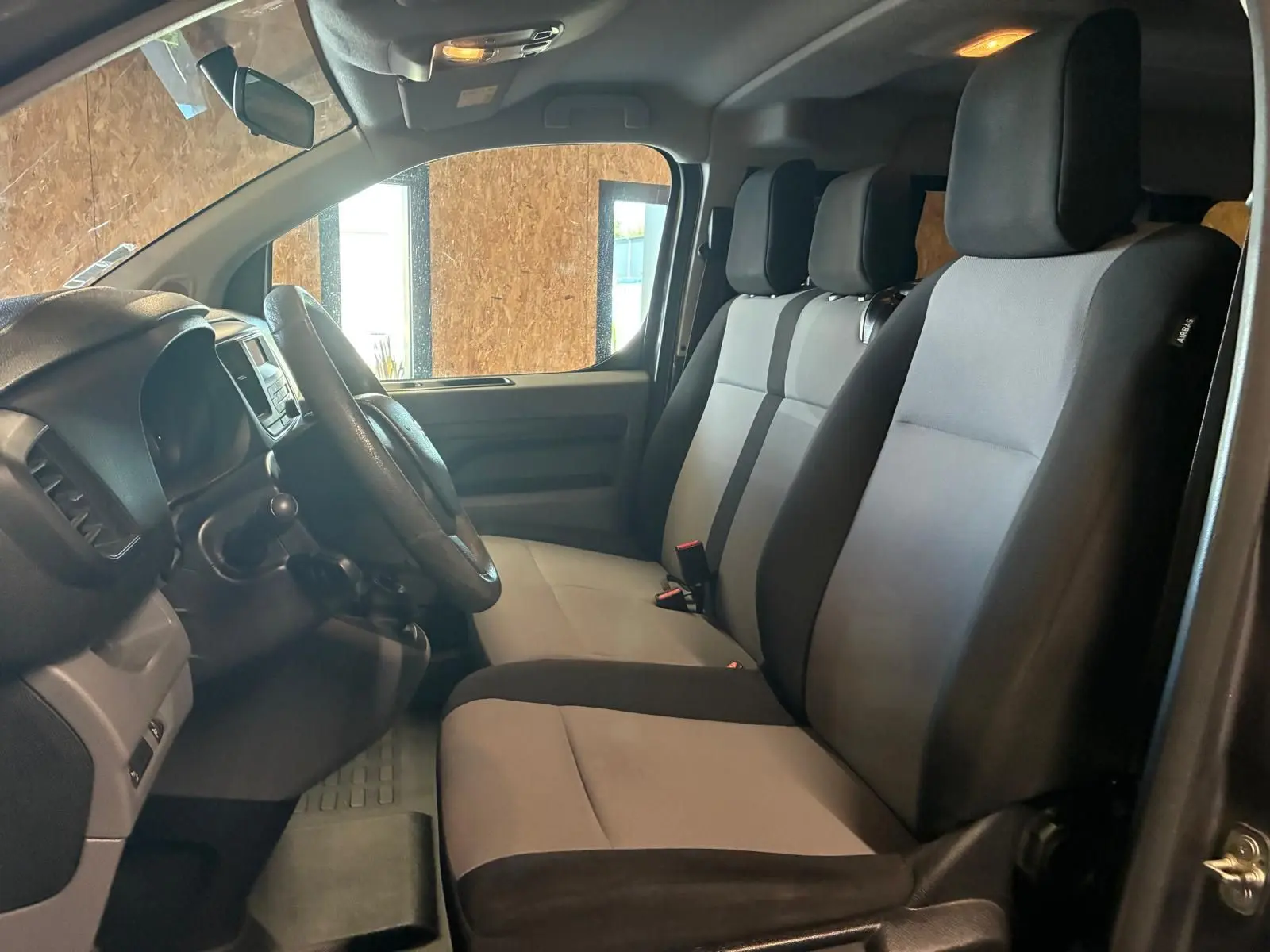 Vue intérieure côté conducteur du Citroën Jumpy XL Spacetourer 2017, sièges tissu gris et noir, volant et tableau de bord visibles.