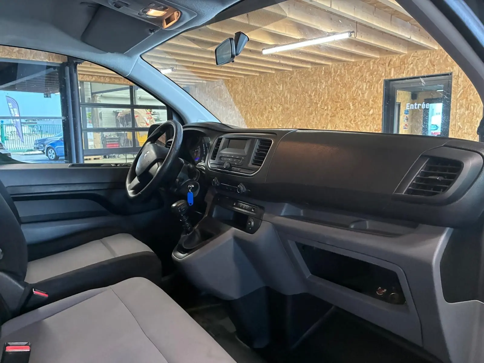 Vue intérieure côté conducteur du Citroën Jumpy gris, mettant en valeur le tableau de bord et la boîte manuelle.