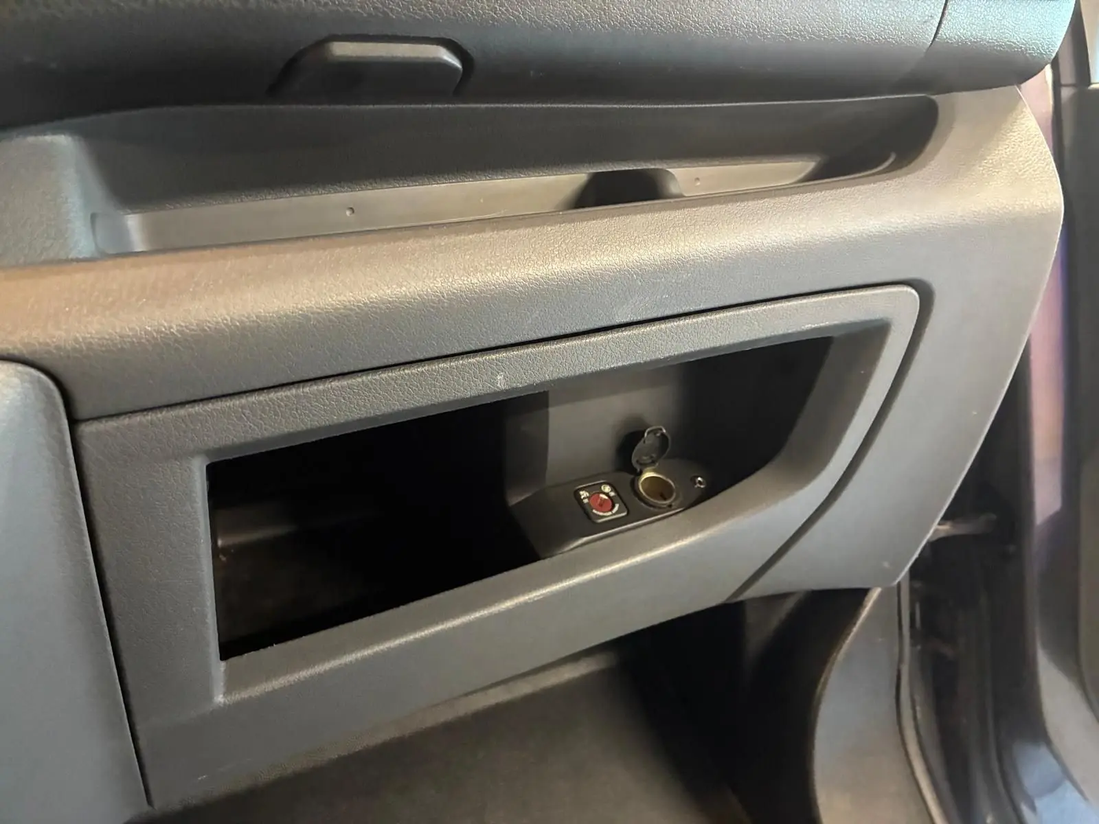 Gros plan sur le rangement côté passager du Citroën Jumpy gris, mettant en valeur une prise allume-cigare ouverte.