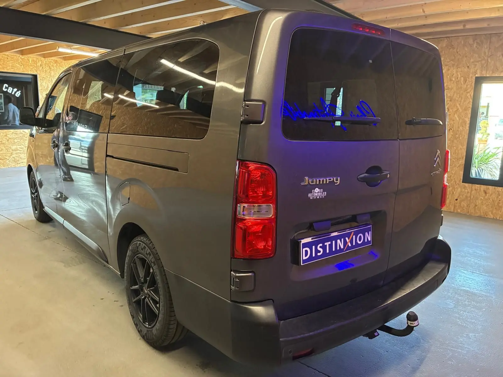 Vue 3/4 arrière droite d’un Citroën Jumpy XL Spacetourer gris, avec hayon fermé et attelage visible en intérieur lumineux.