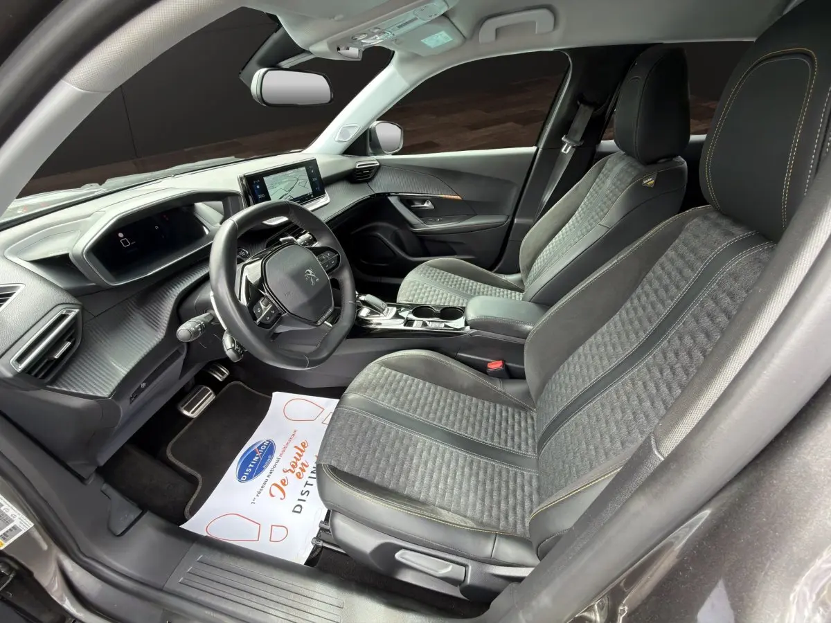 Vue intérieure côté conducteur de la Peugeot 2008 gris foncé, avec sièges tissu et cuir, volant multifonction et écran tactile.
