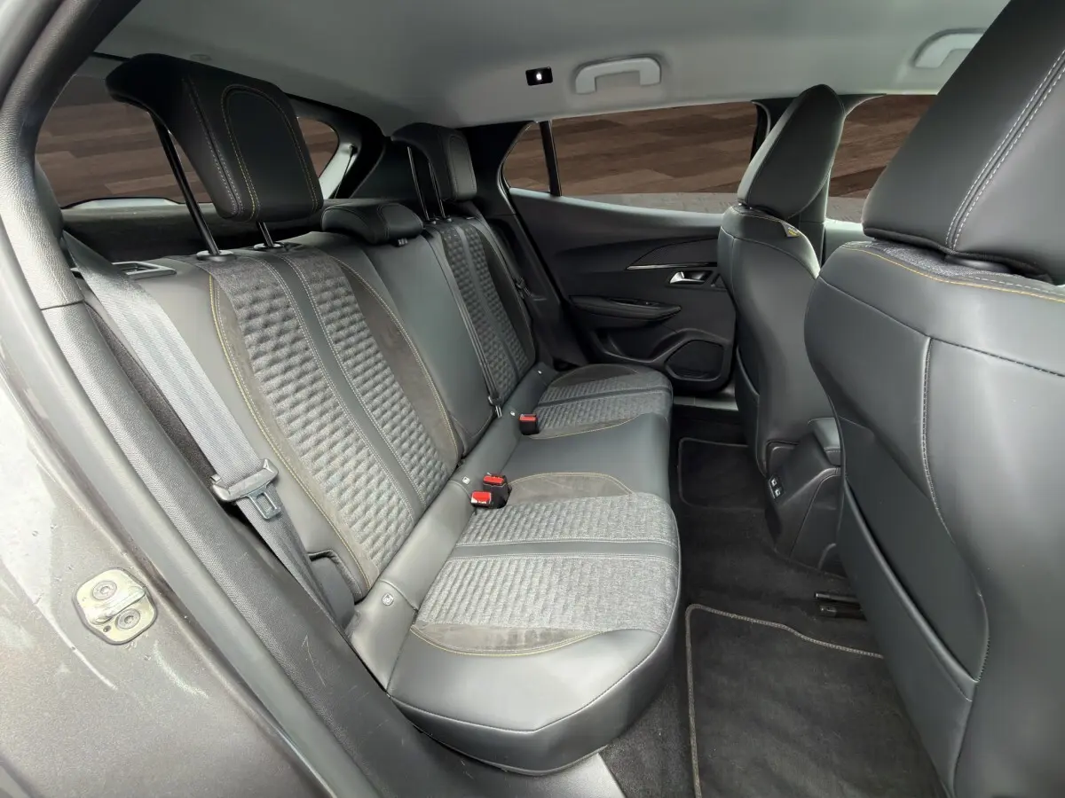 Vue intérieure arrière côté gauche du Peugeot 2008 gris foncé, montrant les sièges en tissu et cuir avec surpiqûres jaunes.