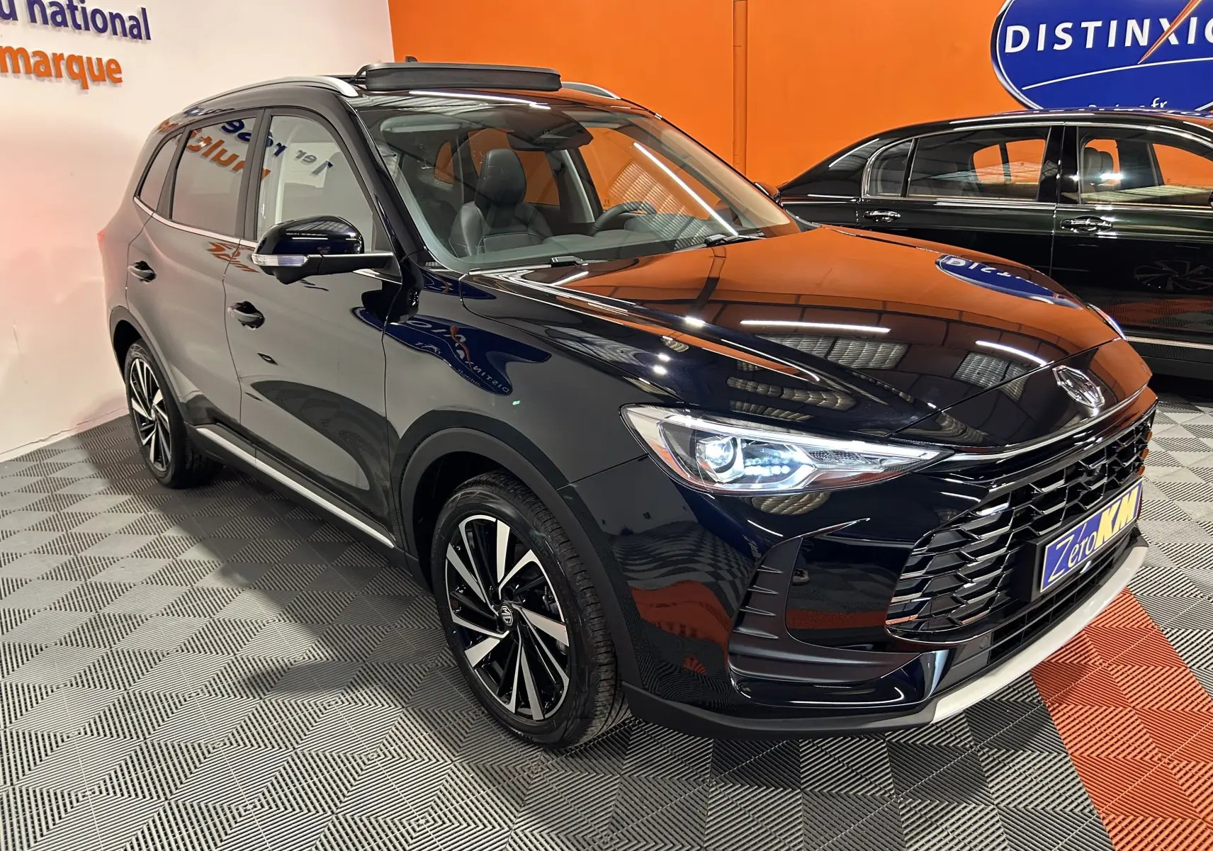 Vue 3/4 avant droite du MG ZS Hybrid+ 197 Luxury Pebble Black avec toit panoramique ouvrant en showroom.