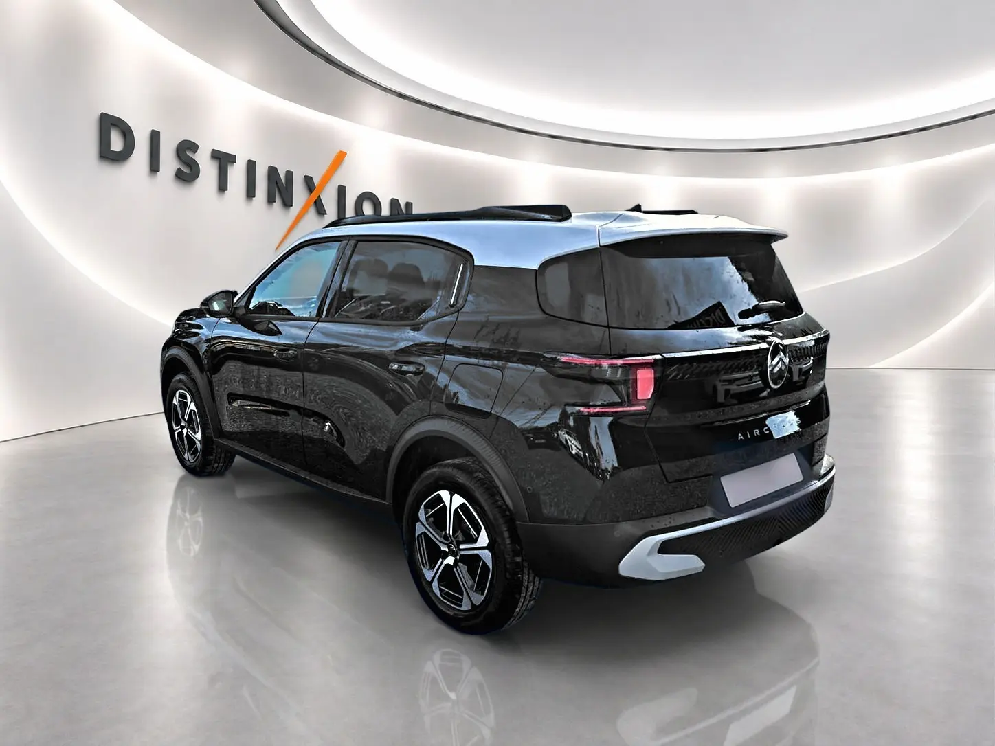 Vue 3/4 arrière droite d'un Citroën C3 Aircross noir avec toit argenté et jantes alu distinctives.