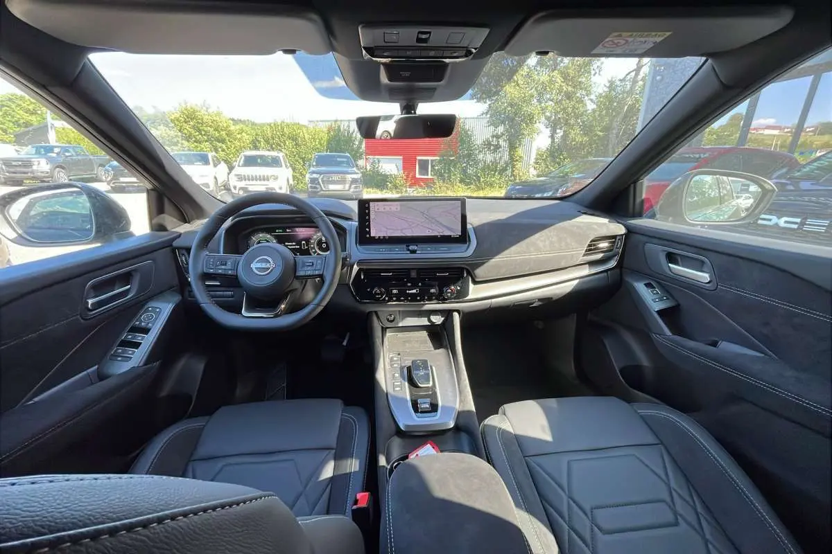 Vue intérieure avant du Nissan Qashqai E-POWER 205 N-DESIGN avec sellerie cuir alcantara noire et écran tactile central.