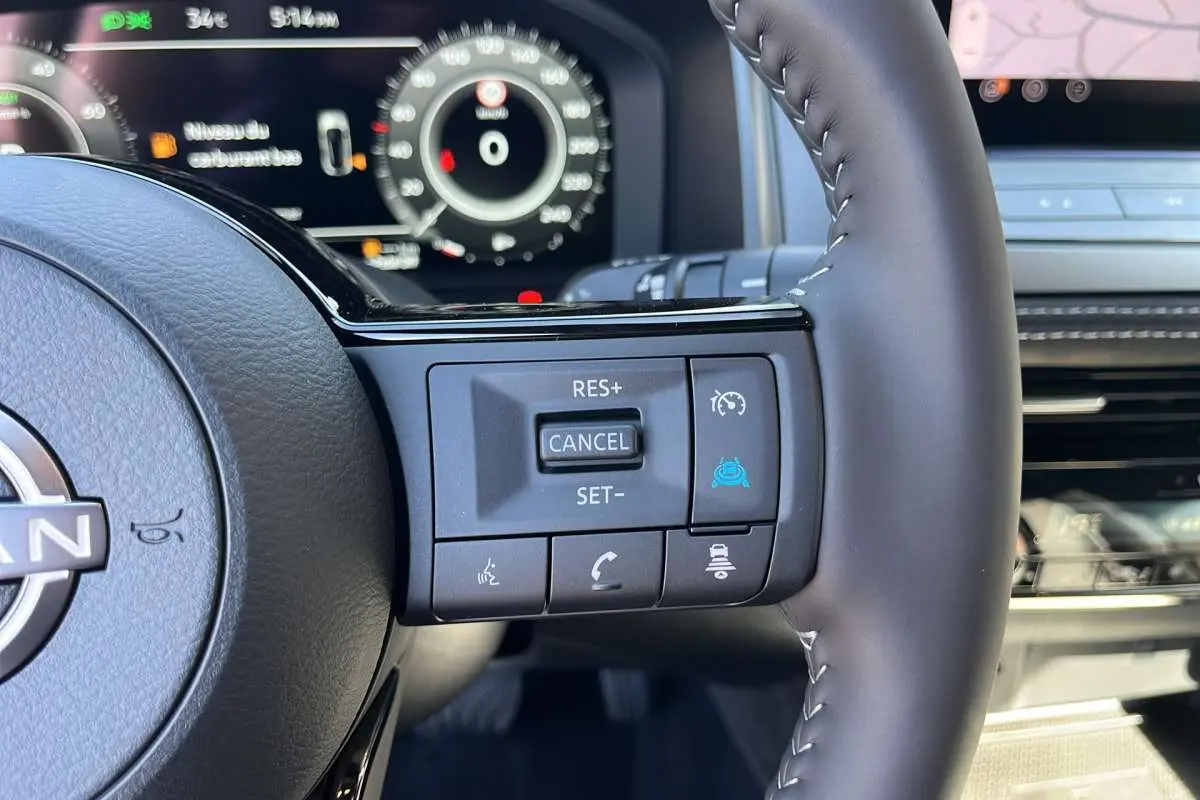 Gros plan sur le volant cuir multifonctions du Nissan Qashqai E-POWER 205 N-DESIGN avec commandes de régulateur et assistance.