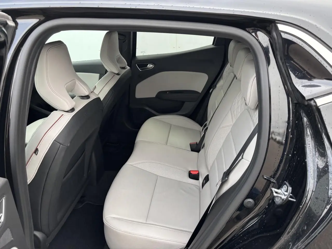 Vue côté gauche de la banquette arrière cuir beige clair dans Renault Clio noire étoile 2020, portes ouvertes.