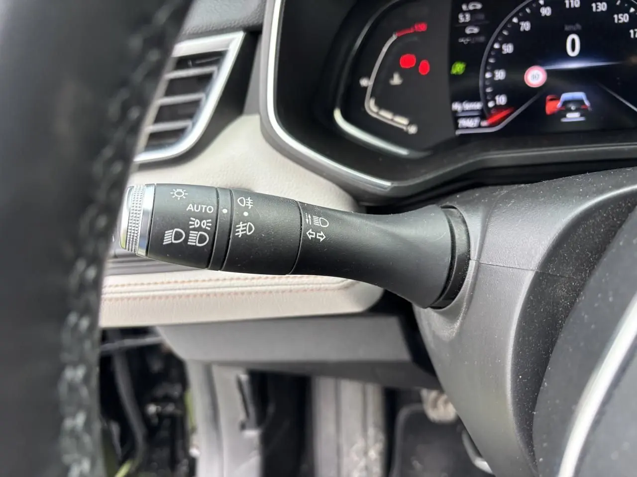 Gros plan sur la commande des feux à gauche du volant dans l'habitacle clair d'une Renault Clio Noir Étoilé 2020.