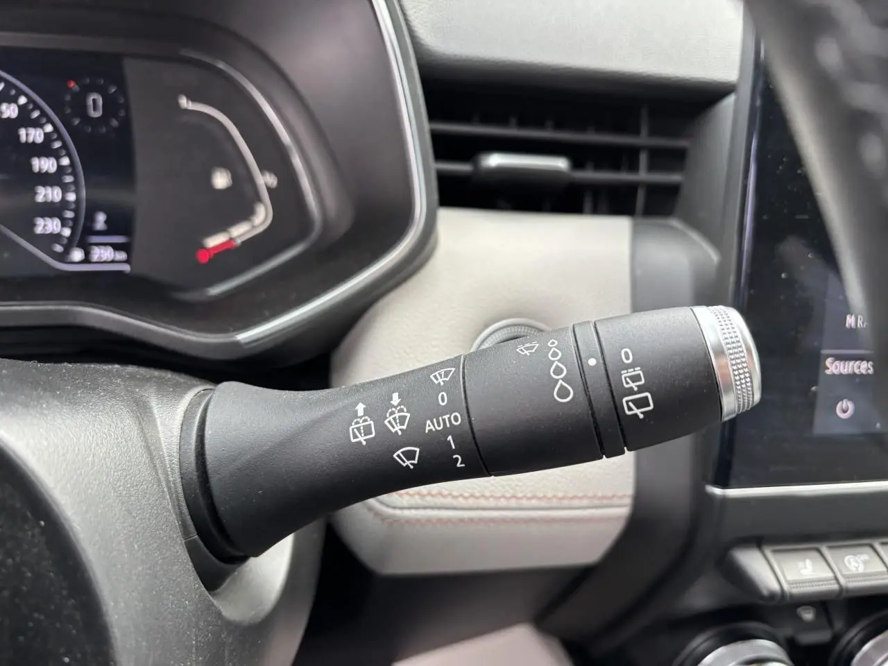 Gros plan sur la commande d’essuie-glaces à gauche du volant dans l’habitacle clair d’une Renault Clio noire étoile 2020.