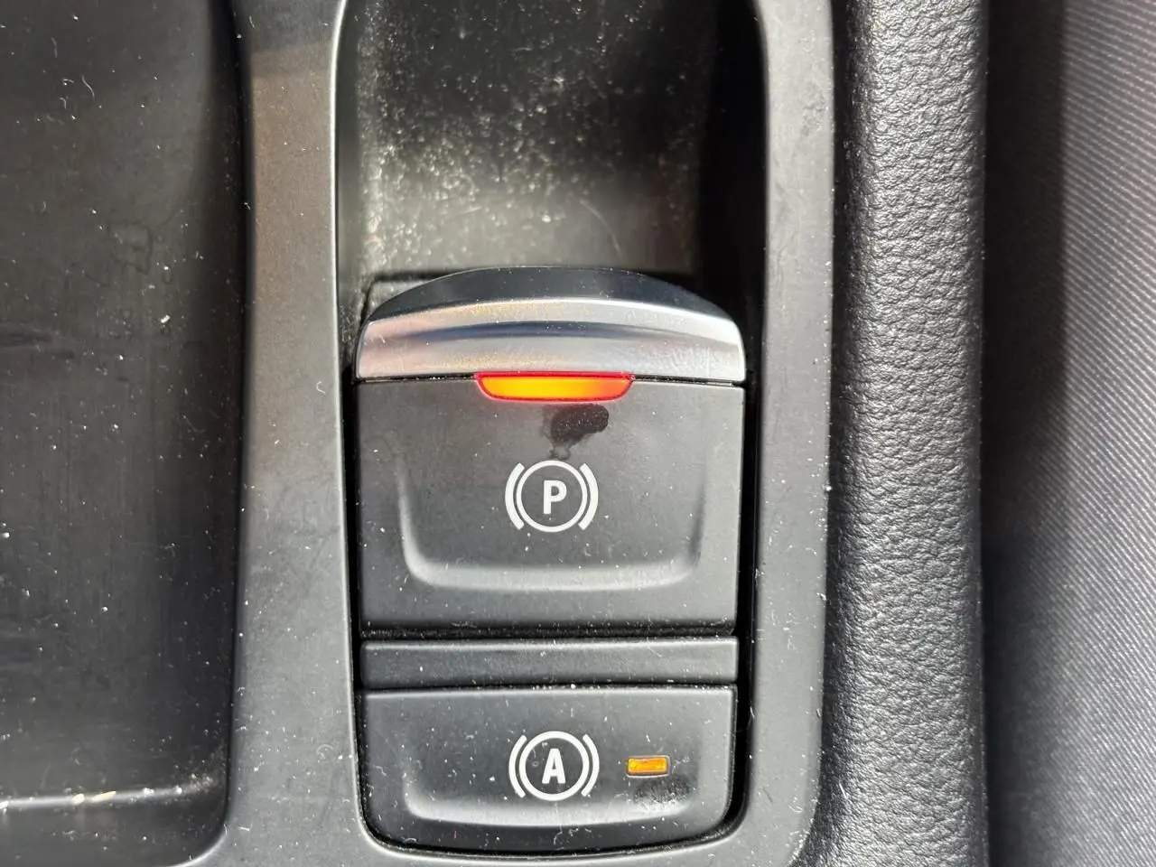 Gros plan sur le bouton du frein de parking électrique activé dans l'habitacle noir de la Renault Clio V 1.0 TCE 100 Initiale Paris.