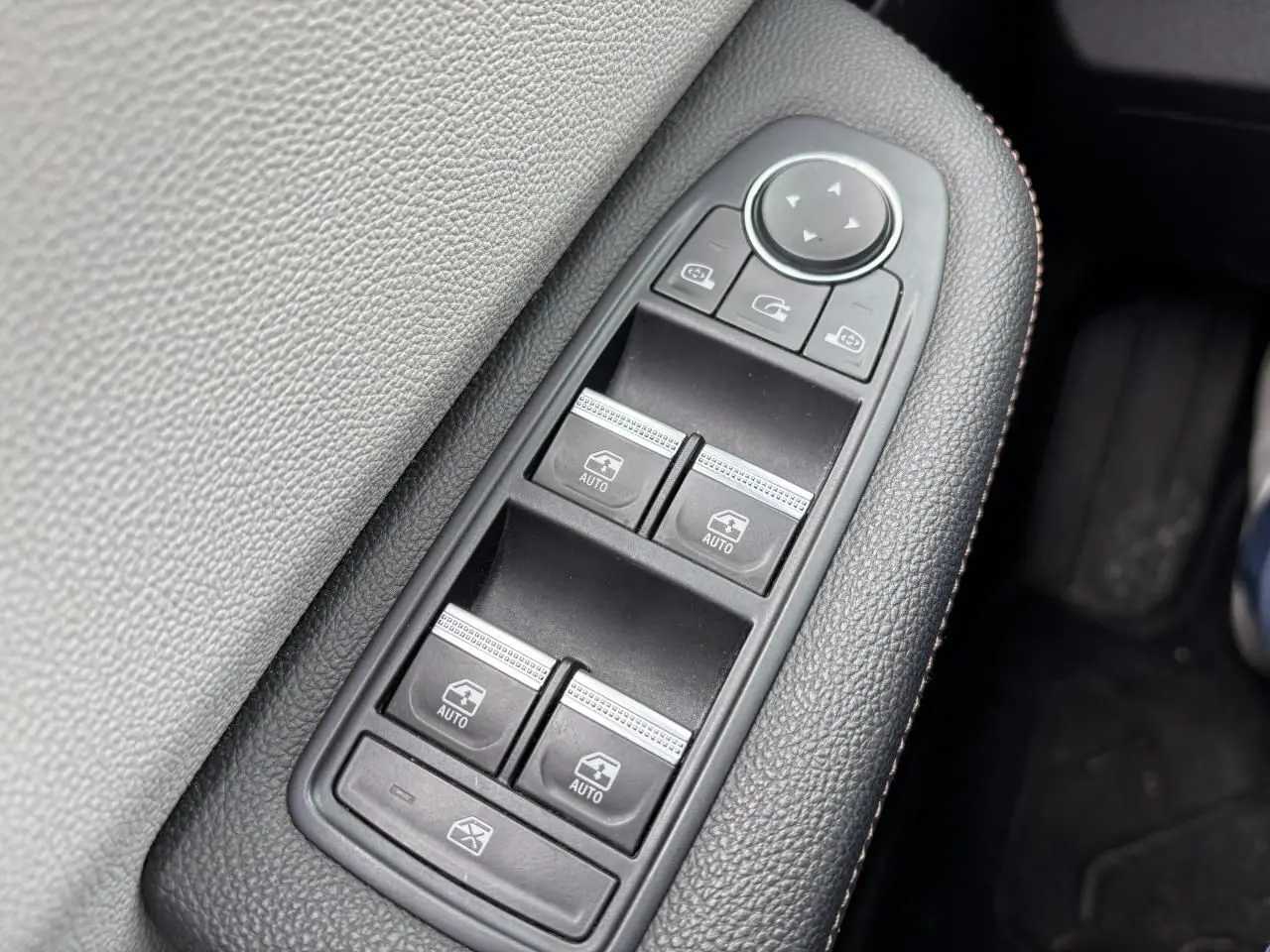 Gros plan sur les commandes des vitres électriques côté conducteur d'une Renault Clio noire étoile, finition Initiale Paris.