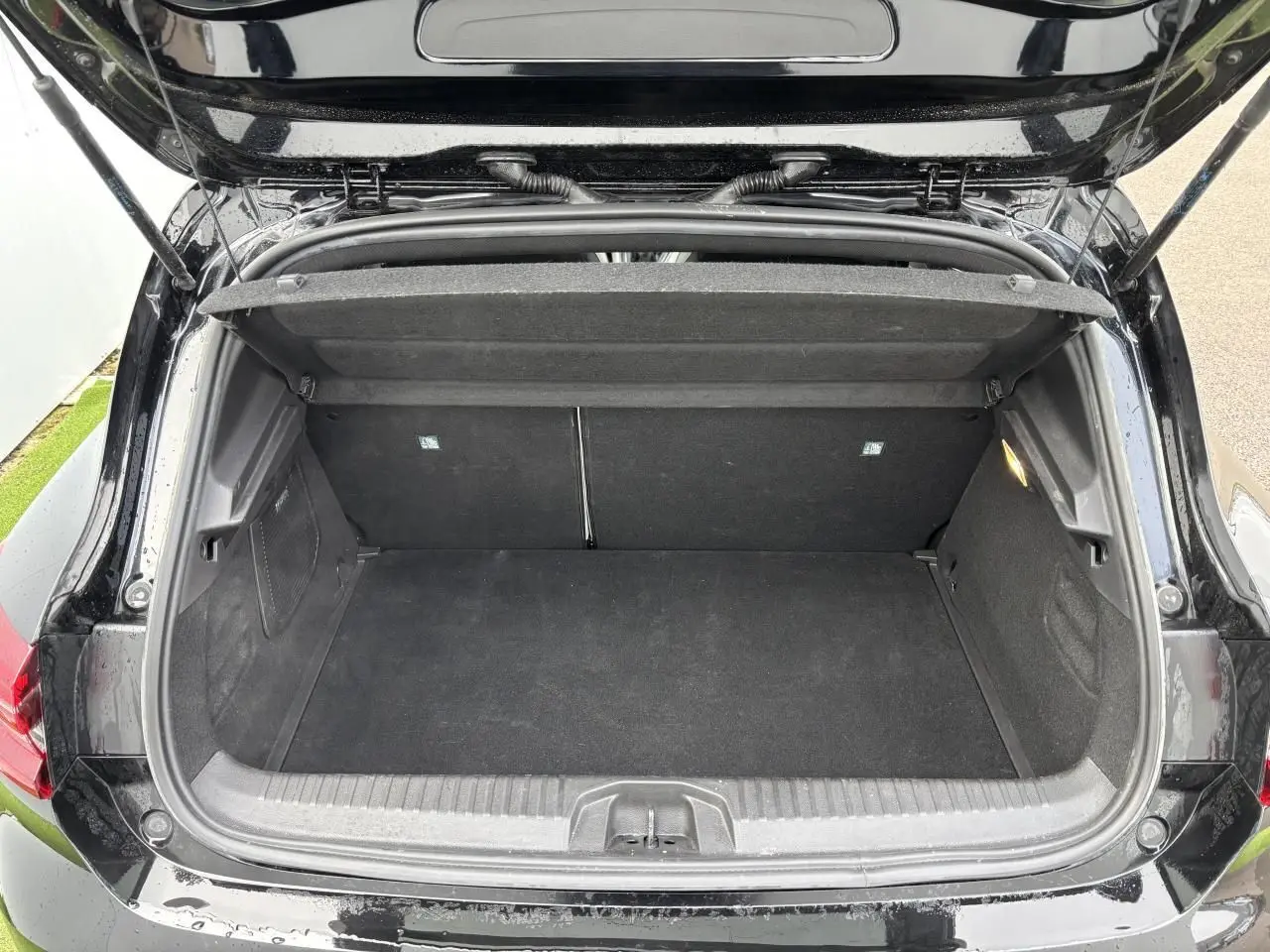 Coffre ouvert vu de l'arrière d'une Renault Clio noire étoile, montrant un espace de rangement propre et vide.