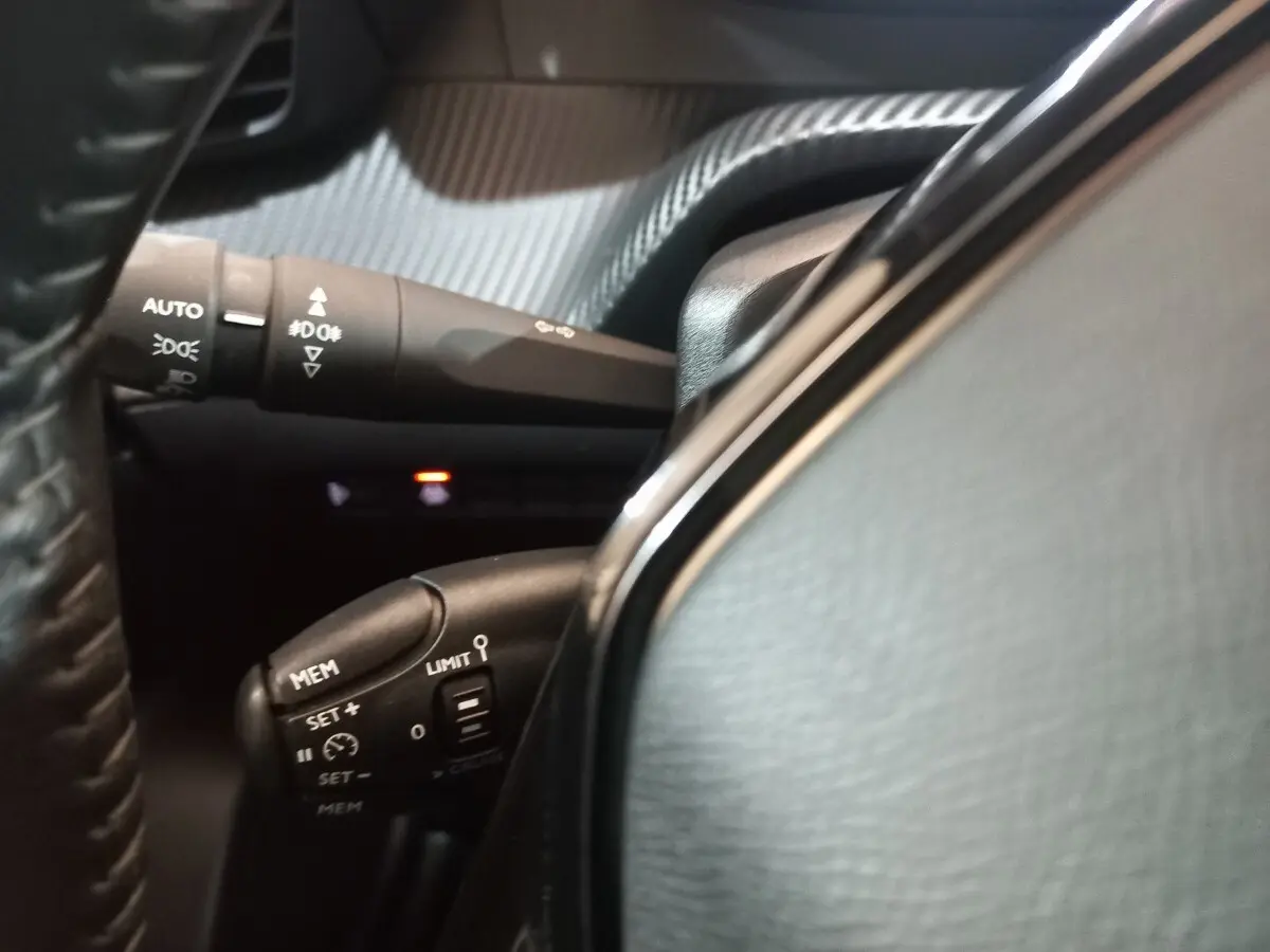 Gros plan sur les commandes au volant du Peugeot 2008 2021, avec cuir noir et boutons multifonctions visibles.