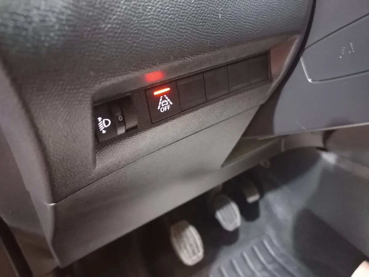 Gros plan sur les commandes sous le tableau de bord côté gauche du Peugeot 2008 orange, avec témoin d'alerte allumé.