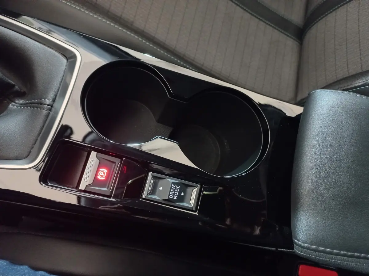 Gros plan sur la console centrale noire de la Peugeot 2008 avec frein à main électrique et bouton Drive Mode.