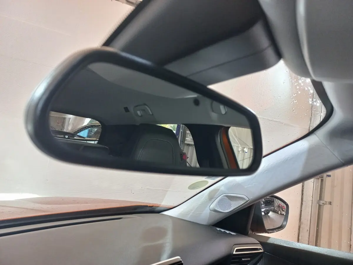 Vue intérieure du rétroviseur central d'un Peugeot 2008 orange 2021, avec siège arrière et partie du tableau de bord visibles.