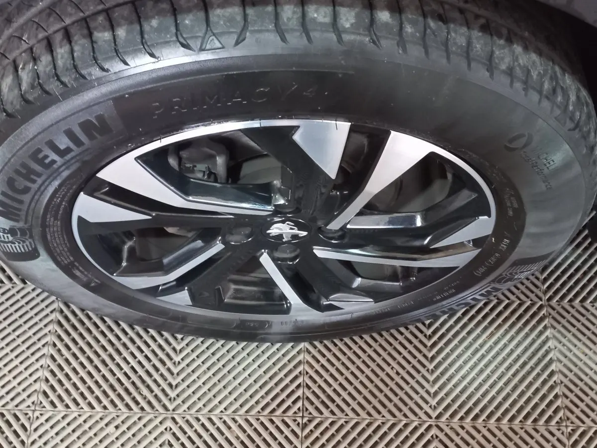 Gros plan sur la roue avant droite de la Peugeot 2008 orange, jante alliage noir et argent avec pneu Michelin.