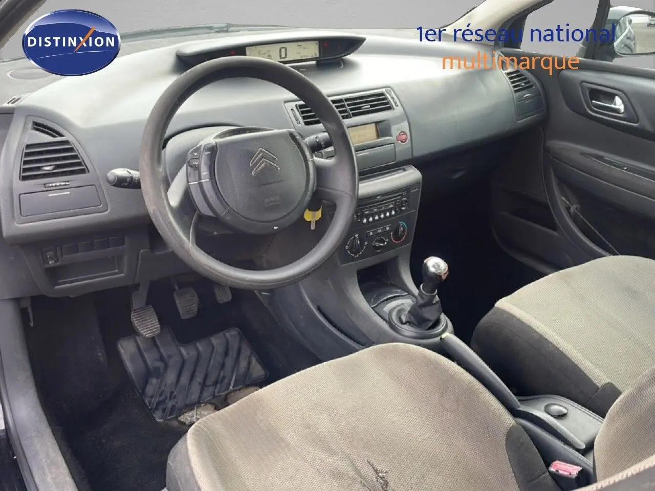 Intérieur de Citroën C4 Coupé 2009 vu côté conducteur, volant, tableau de bord gris et sièges tissu gris clair.
