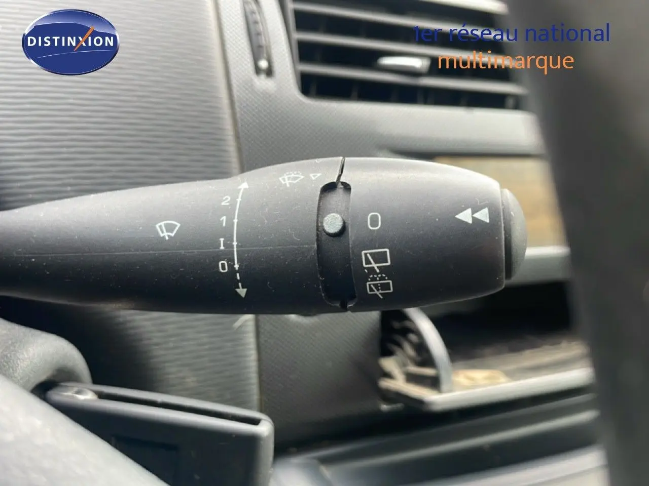 Gros plan sur la commande d’essuie-glace à gauche du volant dans l’habitacle d’une Citroën C4 noir métal de 2009.