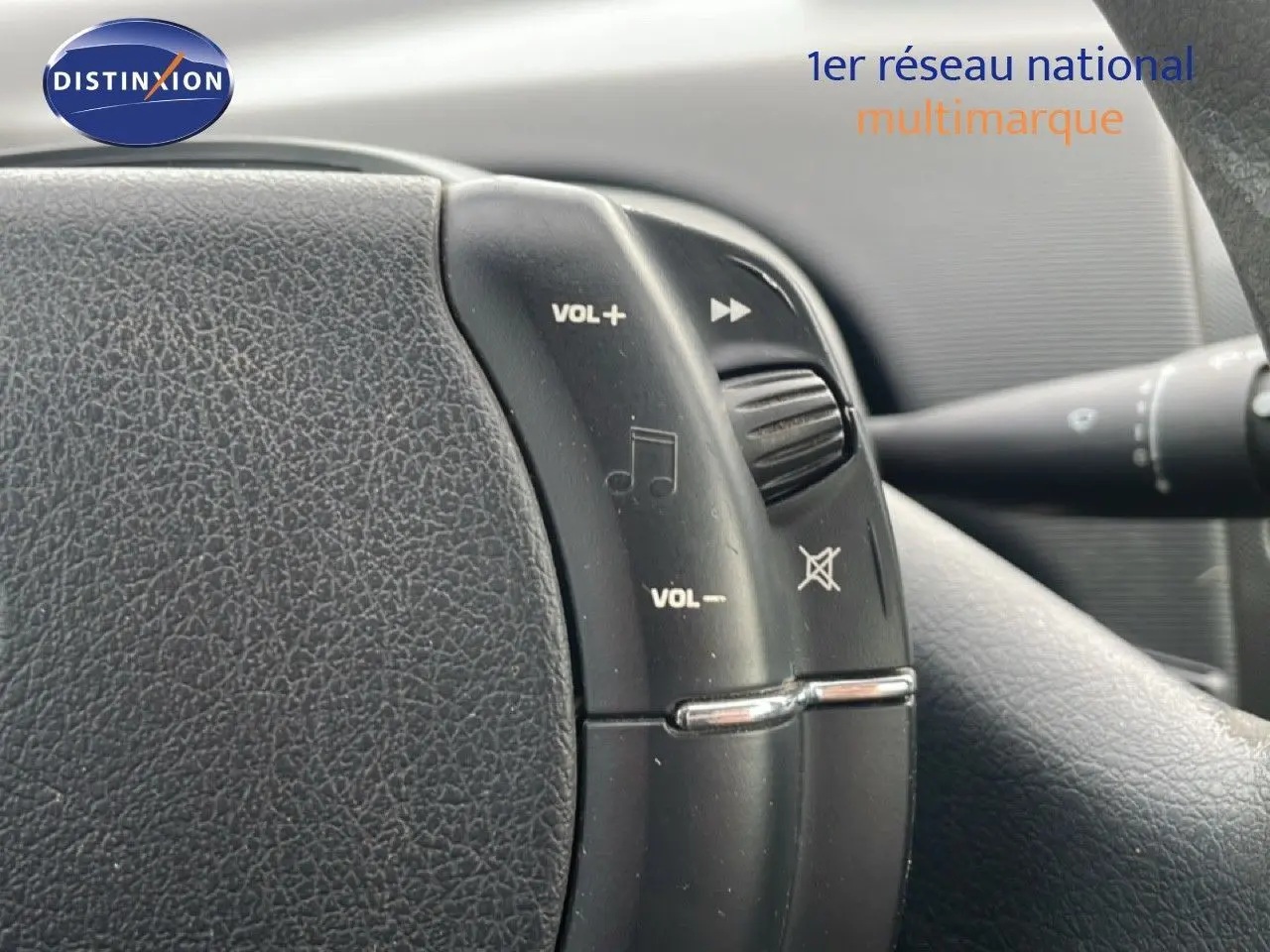 Gros plan sur les commandes audio au volant d'une Citroën C4 Coupé noire métal de 2009, intérieur en tissu gris.